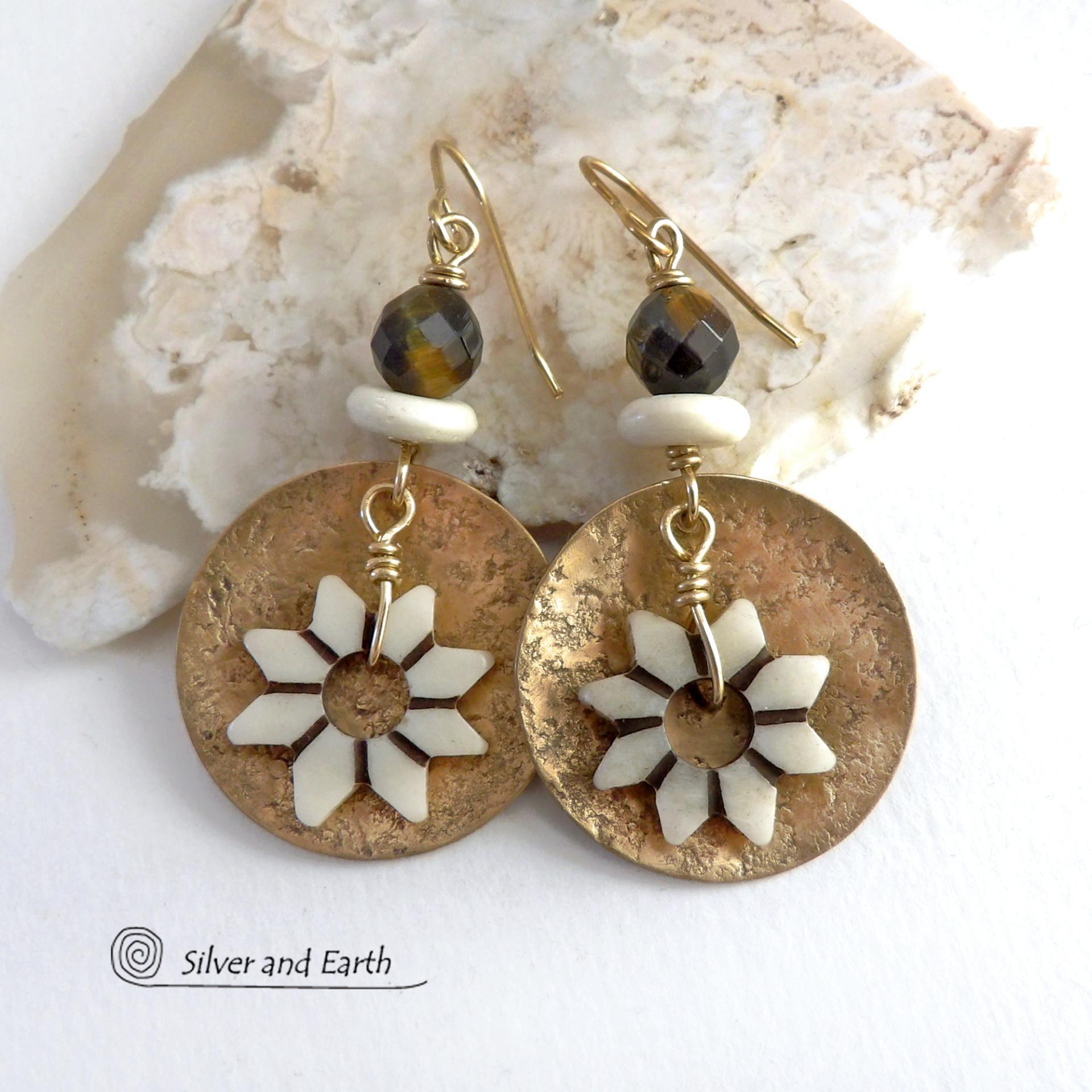 These handmade gold brass earrings have an ethnic bohemian style with an African inspired flair that makes a bold statement. They feature round brass dangles with a lightly hammered texture accented with African flower-shaped bone beads, faceted natural tiger's eye gemstones and African bone beads. Unique and fun to wear, they'll make a great gift for nature lovers and gardeners who love bohemian style jewelry. Handmade in the USA by Silver and Earth Jewelry. 