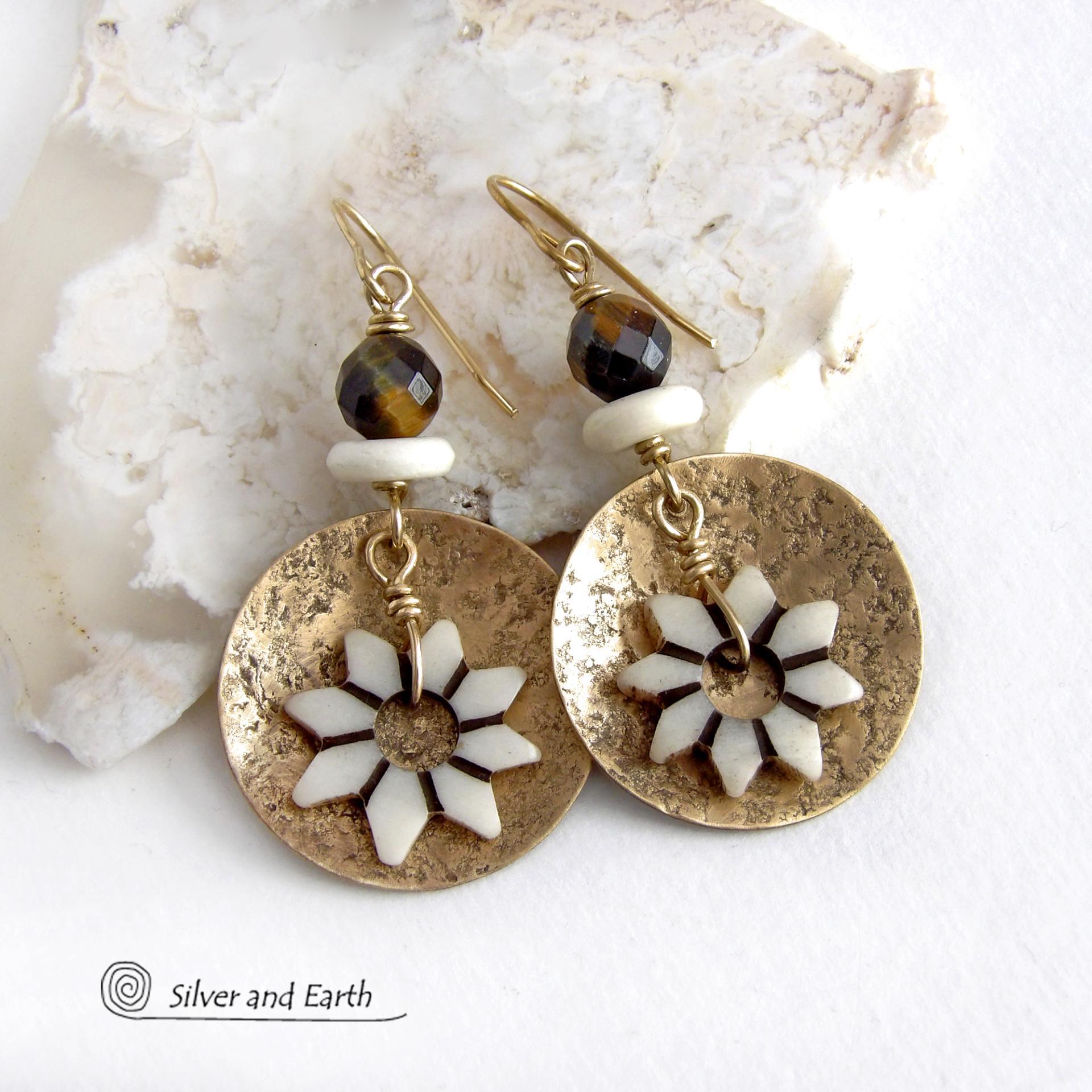 These handmade gold brass earrings have an ethnic bohemian style with an African inspired flair that makes a bold statement. They feature round brass dangles with a lightly hammered texture accented with African flower-shaped bone beads, faceted natural tiger's eye gemstones and African bone beads. Unique and fun to wear, they'll make a great gift for nature lovers and gardeners who love bohemian style jewelry. Handmade in the USA by Silver and Earth Jewelry. 