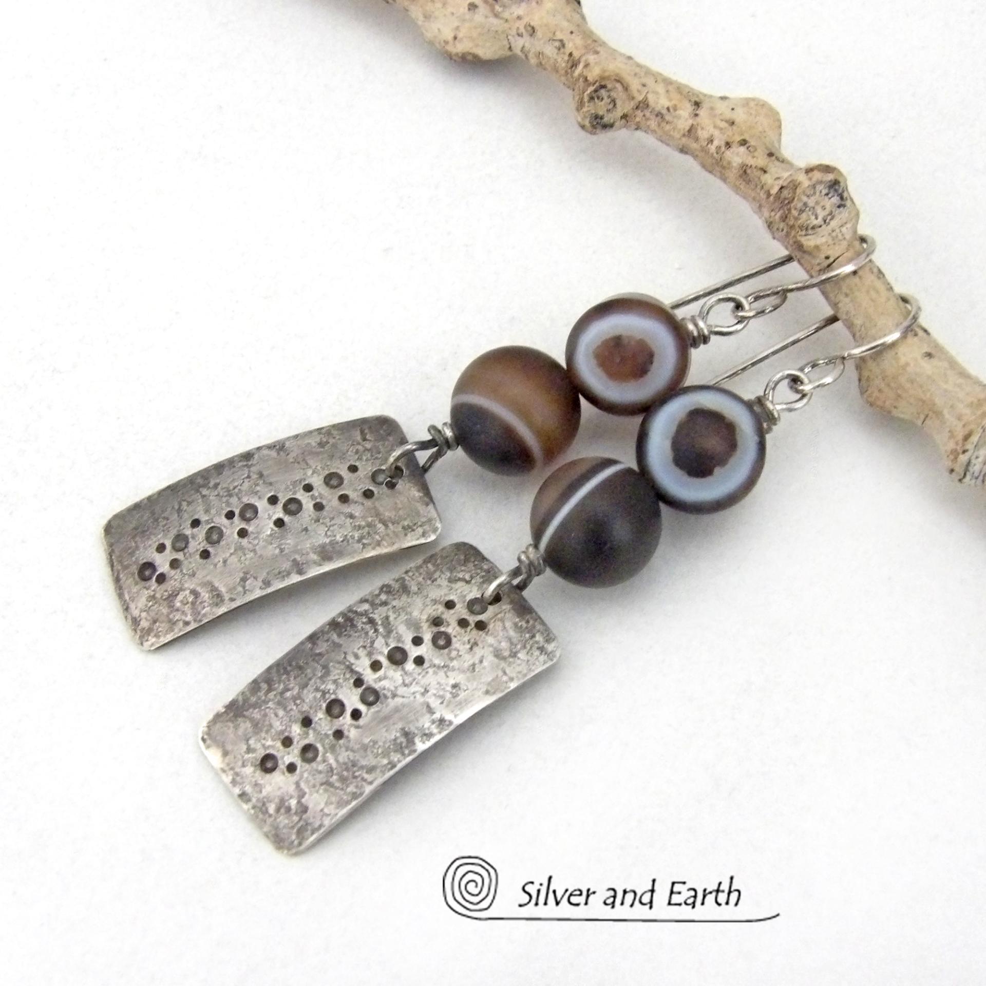 These handcrafted sterling silver earrings feature sterling silver rectangles with a hammered and hand stamped texture accented with natural Botswana agate gemstones. The stones have a smoky brown hue with a natural orbicular "eye" and line pattern. Botswana agate is a unique, banded chalcedony from Southern Africa. Bold and unique, these earrings are one-of-a-kind and will make a striking statement.