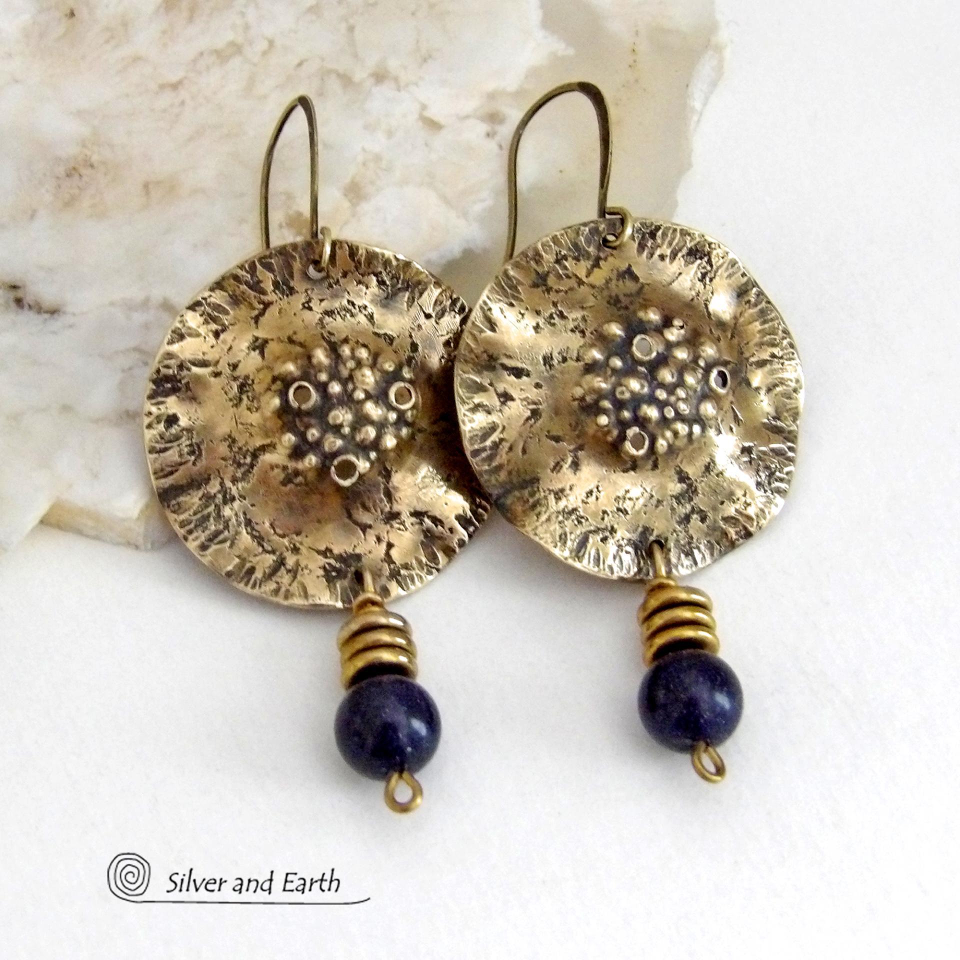 These handcrafted gold brass earrings have a rustic, hammered texture and are accented with dangling dark blue goldstones and small brass beads. They have a modern chic style with an earthy, organic vibe. Goldstone is a man-made stone of quartz sand glass infused with copper particles which creates the subtle sparkle effects. It was invented in Venice, Italy in the seventeenth century. These earrings are perfect for women that love unique, bold one-of-a-kind artisan handmade jewelry. 