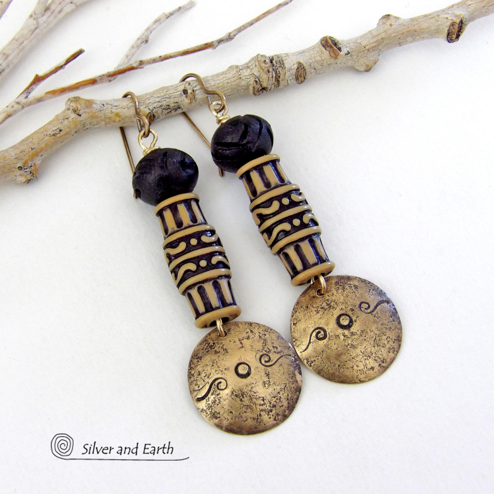 Bold and unique, these handcrafted earrings have an ethnic African tribal vibe. They feature gold brass dangles with a hand stamped and lightly hammered background texture accented with African beads with an intricately carved brownish-black and tan pattern topped off with black African carved bone beads. Unique and fun to wear - they'll make a bold, striking statement. Perfect for women that love to wear one-of-a-kind artisan handcrafted jewelry. Handmade in the USA by Silver and Earth Jewelry.