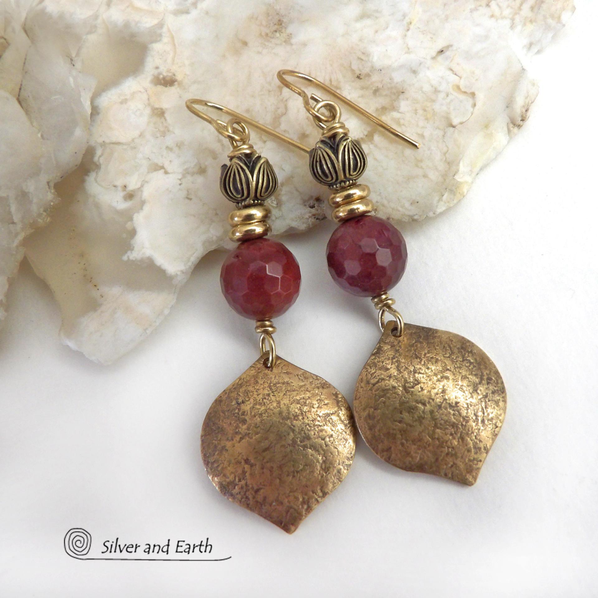 These handcrafted gold brass earrings have a hammered raw silk texture and are accented with micro-faceted burgundy mookaite gemstones, tiny brass beads and tulip flower-shaped beads. Mookaite is a unique, colorful type of jasper that is found at the Mooka Creek in Western Australia. It's known for distinct colors of burgundy, yellows, pinks, and purples. These earrings have a modern elegant chic style that coordinates beautifully with all wardrobe types. Handmade in the USA by Silver and Earth Jewelry. 