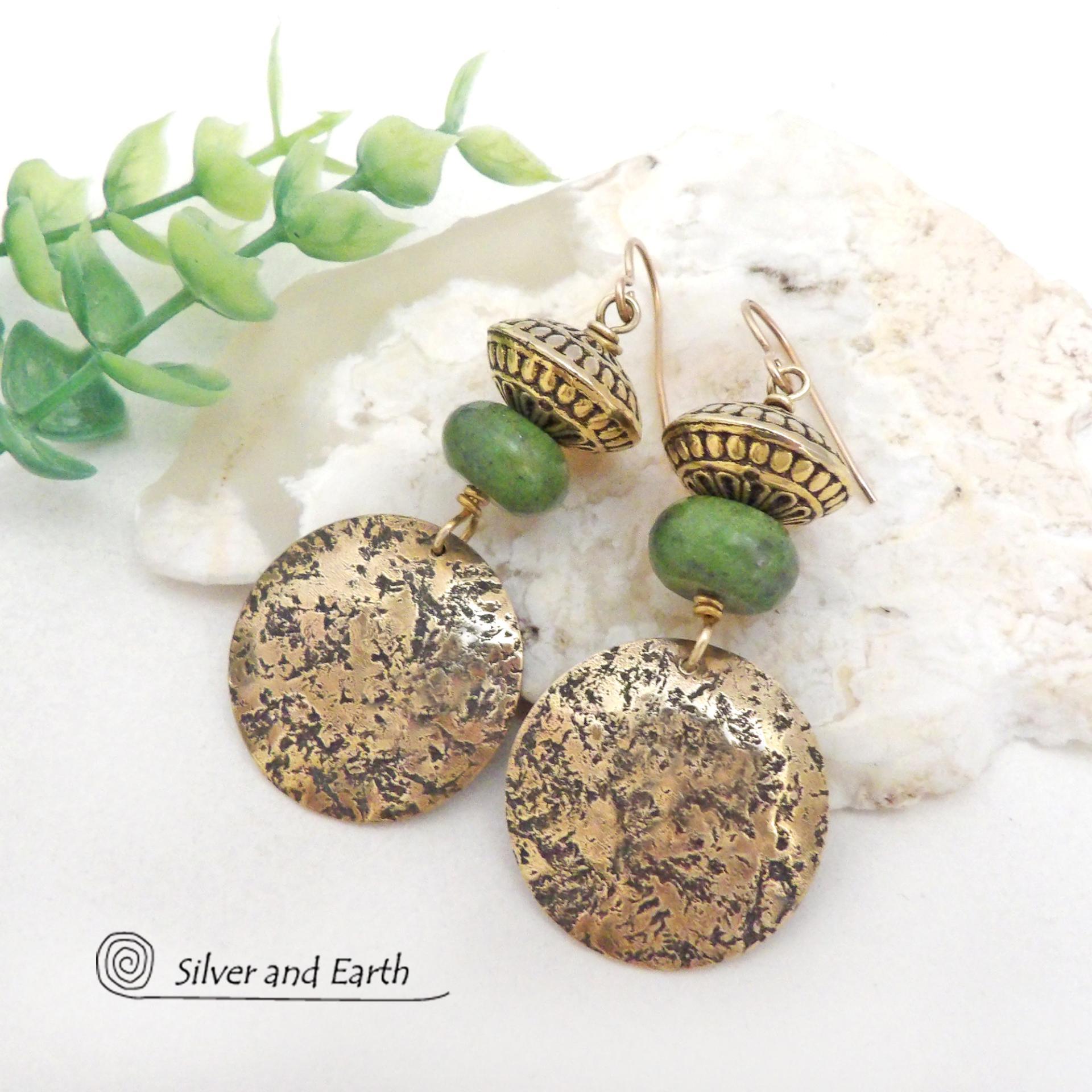These handcrafted earrings feature round gold brass dangles with a lightly hammered organic texture accented with natural green serpentine gemstones and textured brass beads. They have an earthy elegant and modern style that coordinates beautifully with all wardrobe styles. Perfect for your spring wardrobe - or any time of year.