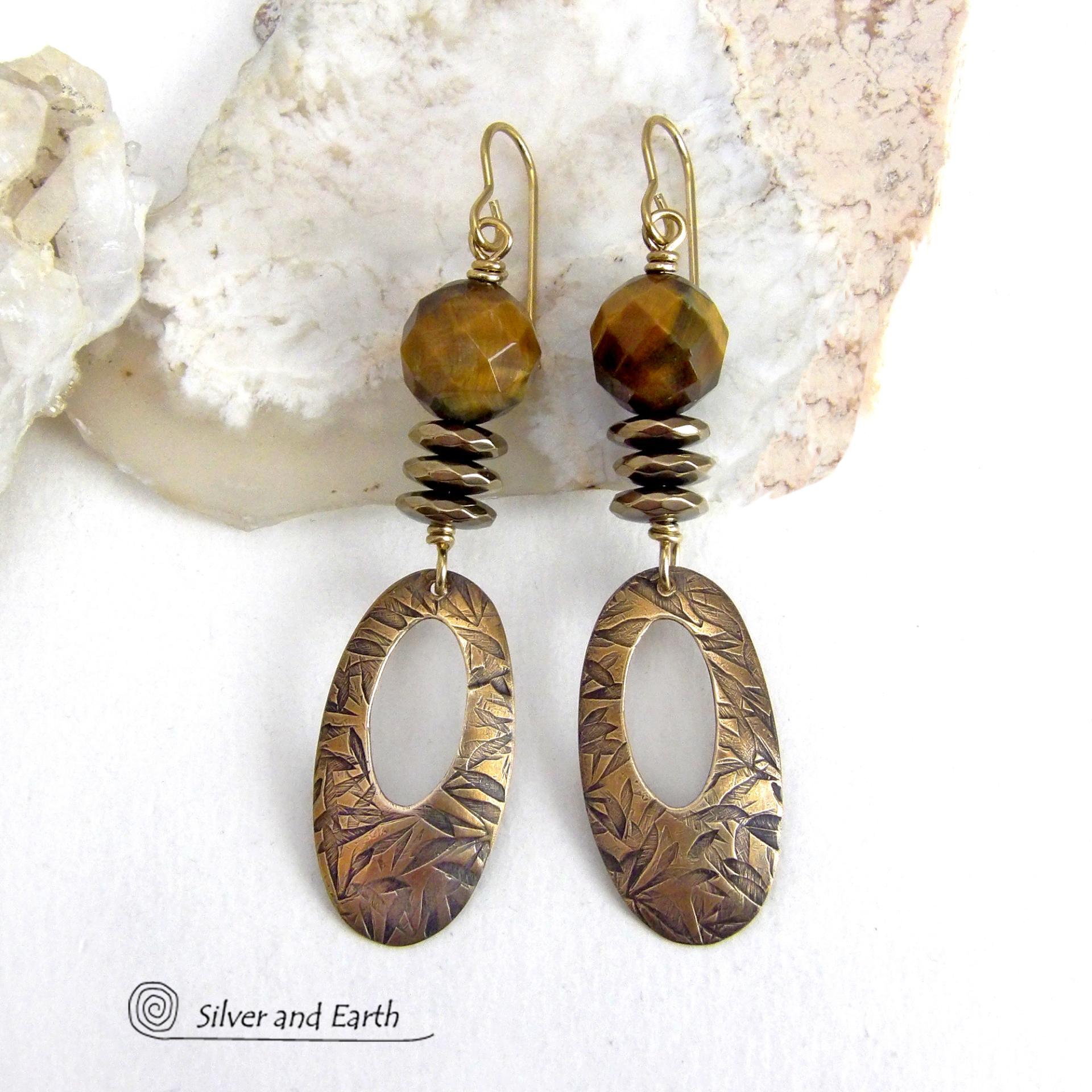 These handcrafted earrings feature gold brass oval hoop dangles with a hand stamped texture accented with natural brown tiger's eye gemstones and faceted hematite stones with an electroplated champagne gold finish. The stones have a beautiful brown hue with undertones of gold and a faceted finish which casts off a natural sparkle and shine. They have a modern, chic and elegant style that coordinates beautifully with all wardrobe types - dressed up or down.