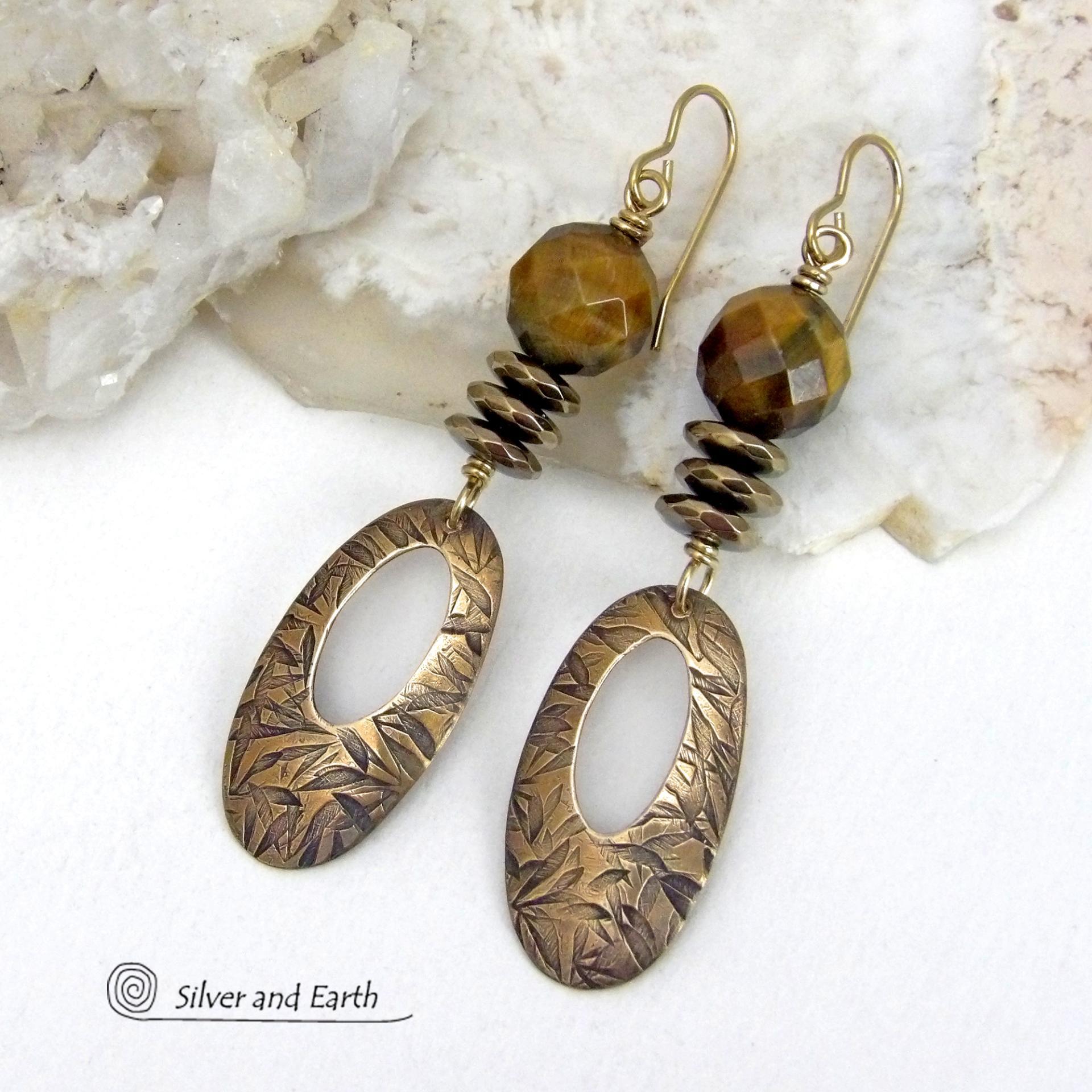 These handcrafted earrings feature gold brass oval hoop dangles with a hand stamped texture accented with natural brown tiger's eye gemstones and faceted hematite stones with an electroplated champagne gold finish. The stones have a beautiful brown hue with undertones of gold and a faceted finish which casts off a natural sparkle and shine. They have a modern, chic and elegant style that coordinates beautifully with all wardrobe types - dressed up or down.