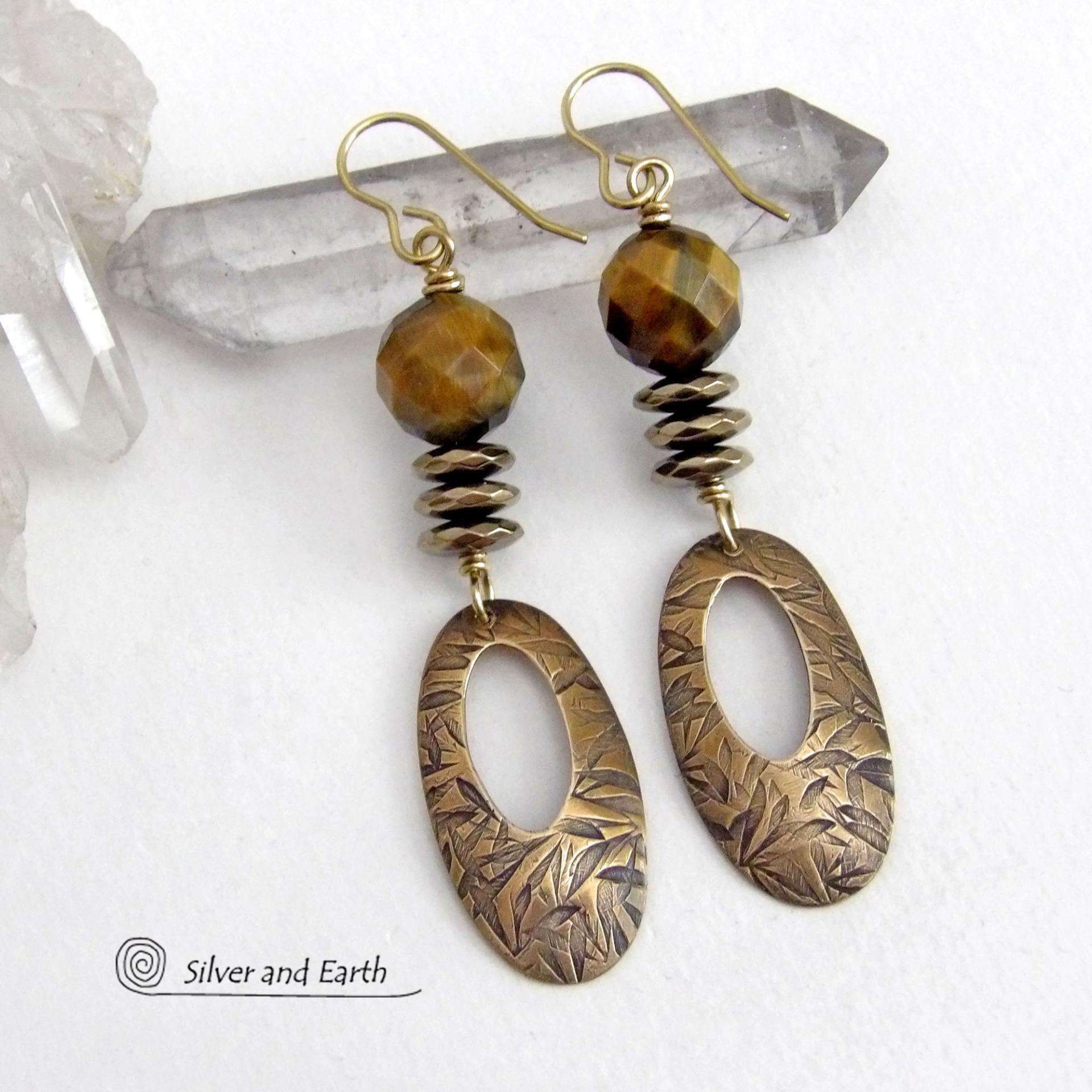 These handcrafted earrings feature gold brass oval hoop dangles with a hand stamped texture accented with natural brown tiger's eye gemstones and faceted hematite stones with an electroplated champagne gold finish. The stones have a beautiful brown hue with undertones of gold and a faceted finish which casts off a natural sparkle and shine. They have a modern, chic and elegant style that coordinates beautifully with all wardrobe types - dressed up or down.