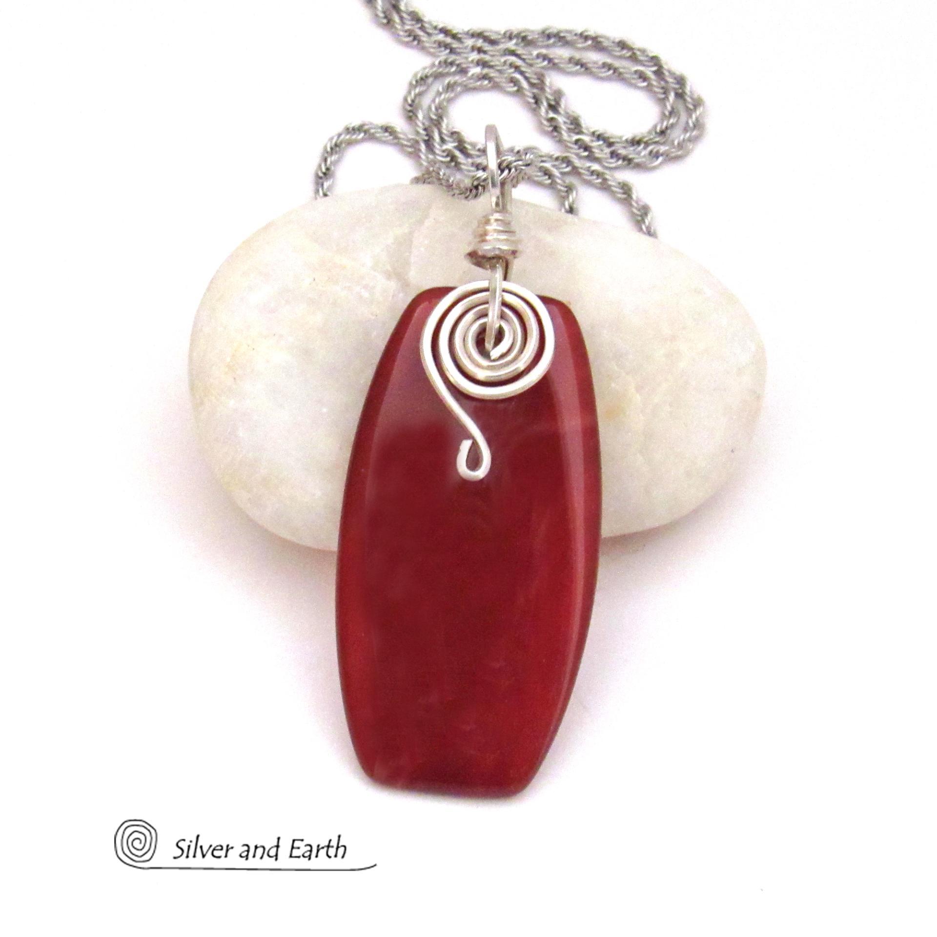 This handcrafted carnelian gemstone necklace has a modern chic flair. It features a natural carnelian gemstone with a dark burnt orange hue accented with a hand forged sterling silver spiral accent and sterling silver wire bail. 