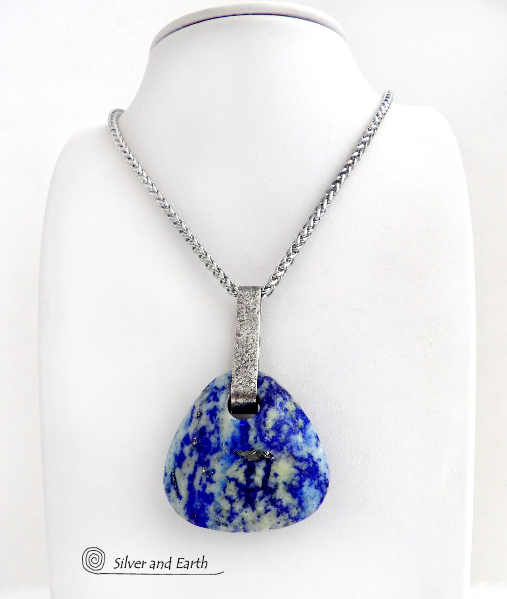 This one-of-a-kind necklace features a gorgeous, chunky and thick natural lapis lazuli gemstone accented with a handcrafted sterling silver bail with a lightly hammered organic texture. The stone is a beautiful shade of blue with white inclusions and a sprinkling of natural sparkly pyrite inclusions and a faceted finish. The stone is equally gorgeous on both sides, so I designed it to be reversible. (See all photos for alternate sides). Pendant comes on a 20" stainless steel chain necklace. 