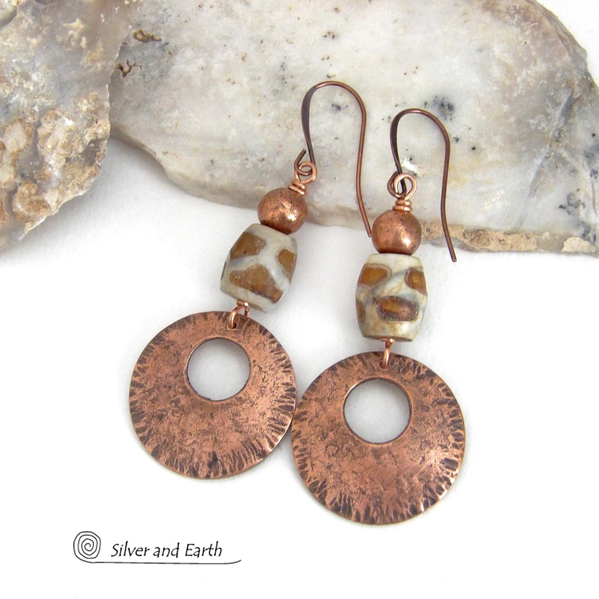These handcrafted copper earrings have a bold, ethnic African style and flair. They feature round copper dangles with a rustic hammered texture accented with African etched giraffe print agate stones topped off with solid copper beads. Unique and striking, they'll make a bold statement. Perfect for women that love ethnic tribal style jewelry. Your choice of ear wire - copper or hypoallergenic niobium.