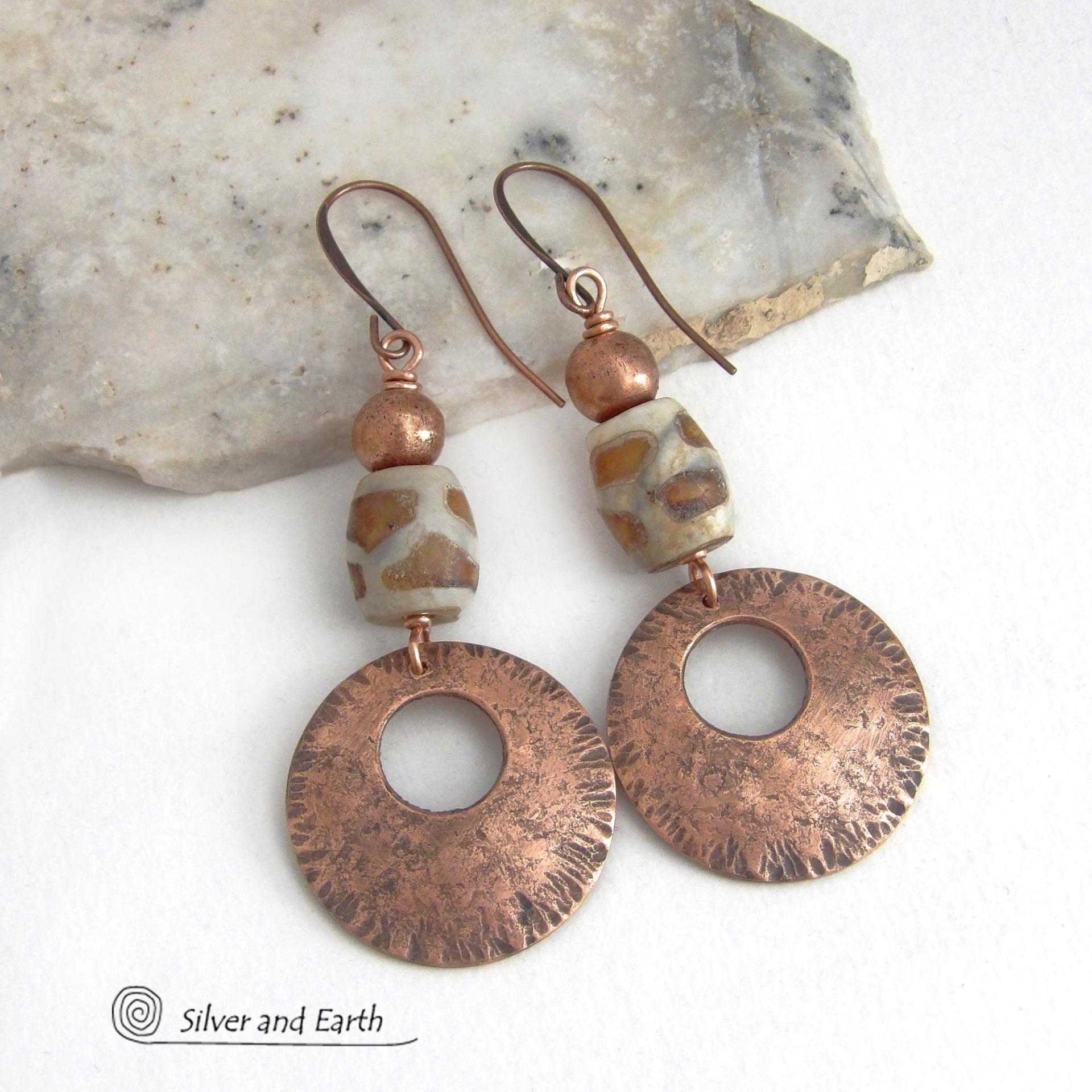 These handcrafted copper earrings have a bold, ethnic African style and flair. They feature round copper dangles with a rustic hammered texture accented with African etched giraffe print agate stones topped off with solid copper beads. Unique and striking, they'll make a bold statement. Perfect for women that love ethnic tribal style jewelry. Your choice of ear wire - copper or hypoallergenic niobium.