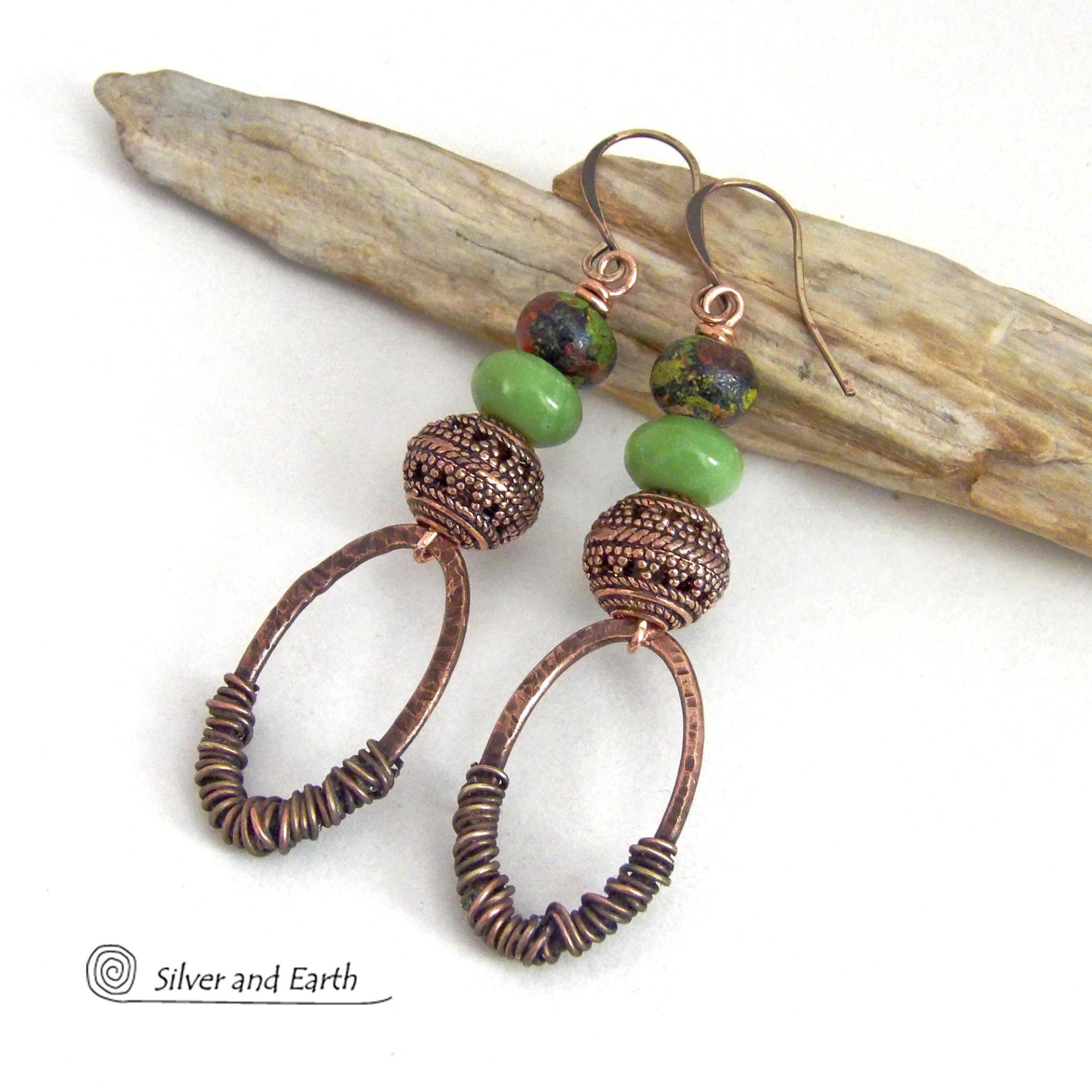 These handmade earrings feature wire wrapped copper oval hoops accented with copper filigree beads, green serpentine gemstones and hand painted wood beads. They have a bold exotic vibe with an ethnic tribal flair and are sure to make a unique statement.