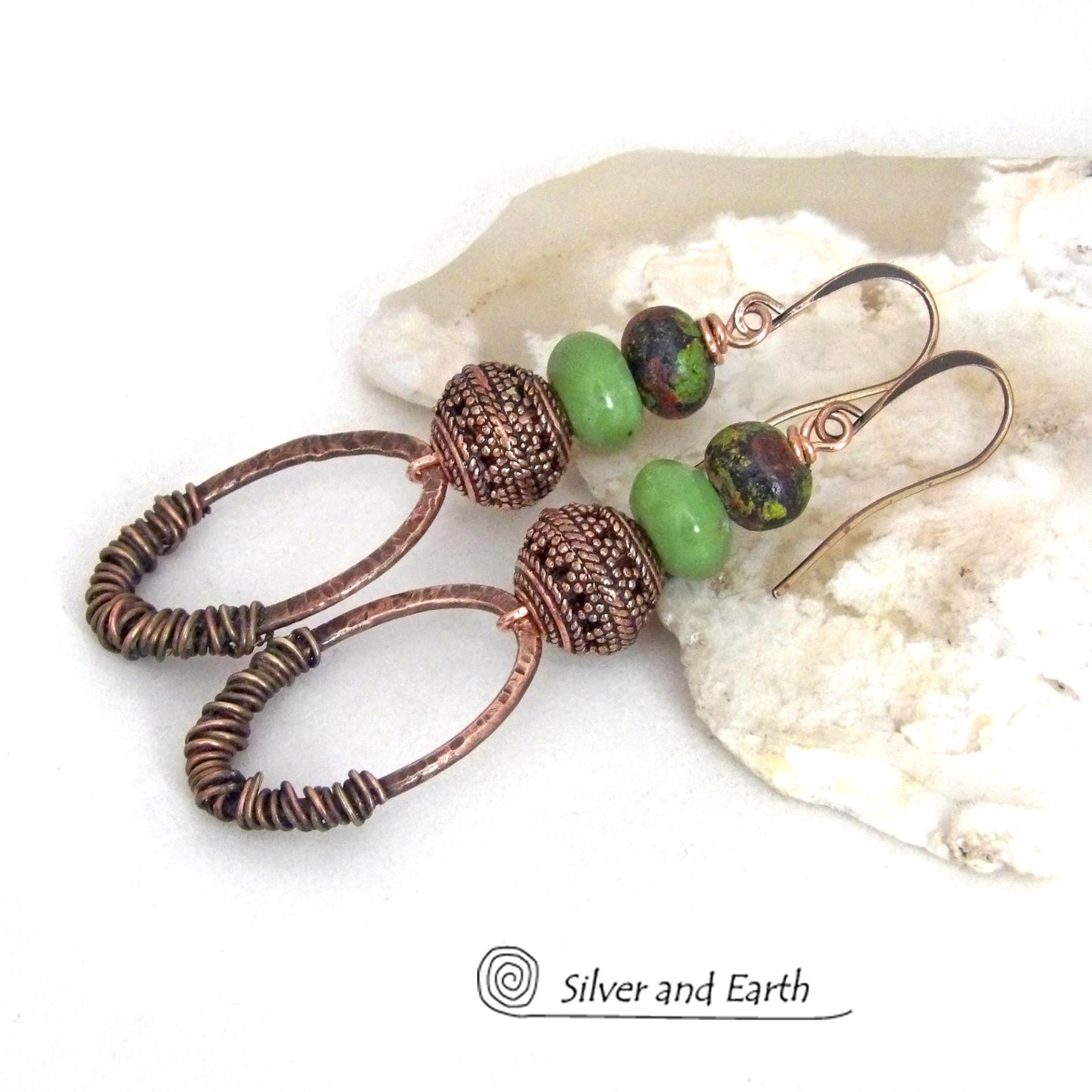 These handmade earrings feature wire wrapped copper oval hoops accented with copper filigree beads, green serpentine gemstones and hand painted wood beads. They have a bold exotic vibe with an ethnic tribal flair and are sure to make a unique statement.
