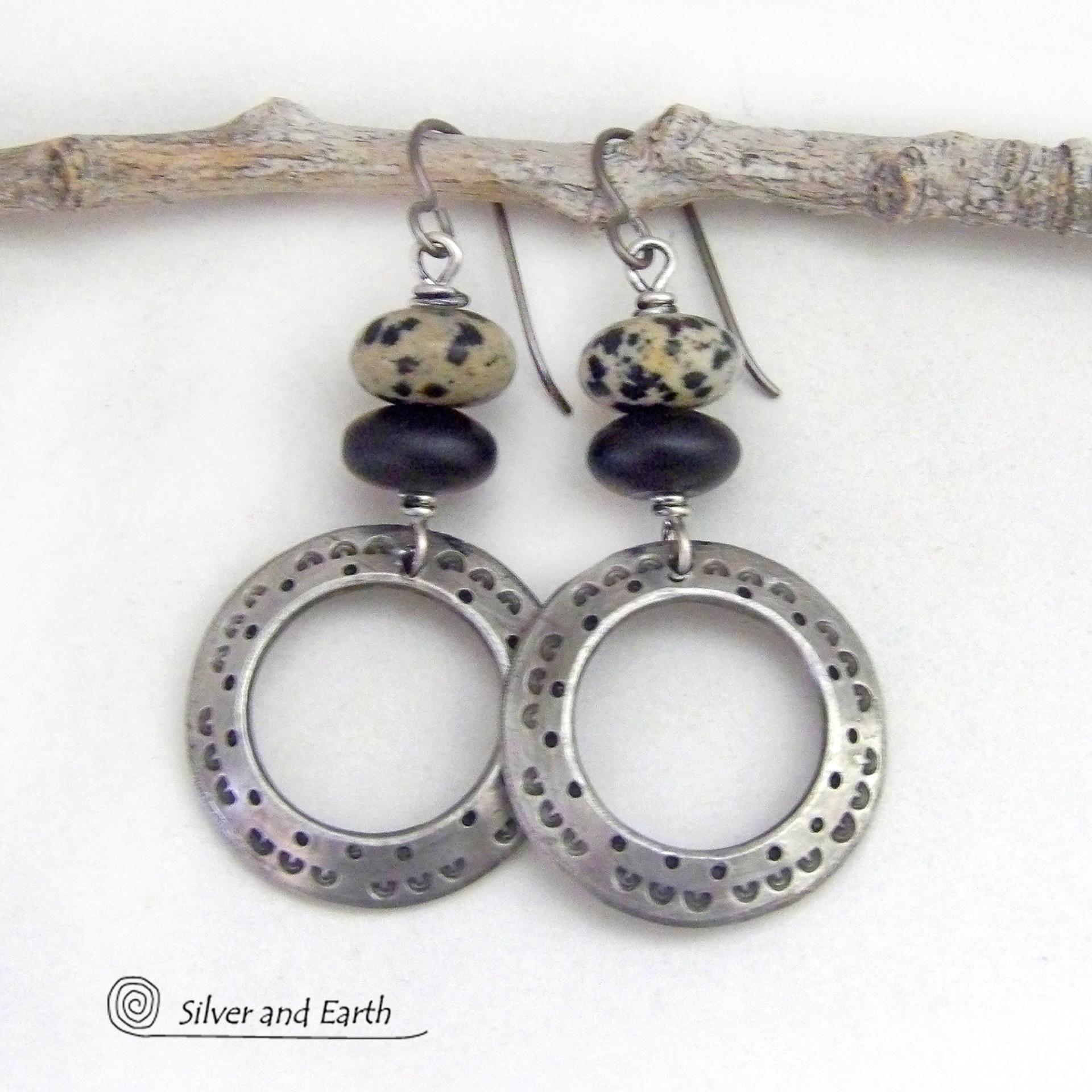 These handcrafted silver pewter hoop earrings have a hand stamped texture accented with natural dalmatian jasper gemstones and matte black glass beads. This type of jasper is known for its spotted pattern that resembles the Dalmatian breed of dog. These earrings have a modern, earthy boho chic style that coordinates beautifully with all wardrobe styles. Handmade the USA by Silver and Earth Jewelry.