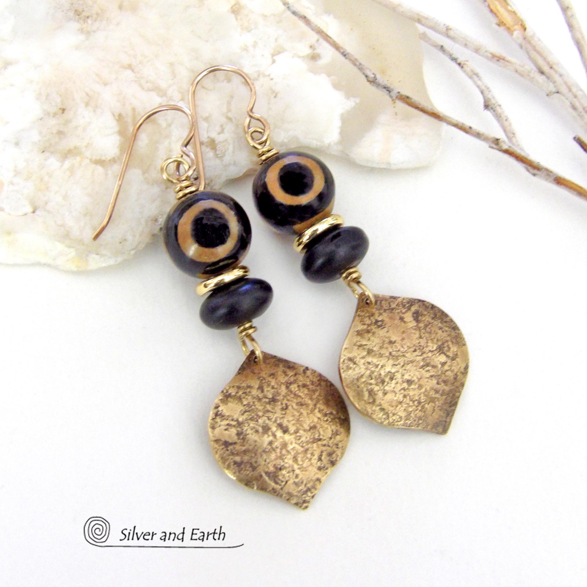 These handcrafted gold brass earrings have a contemporary modern style with an ethnic boho vibe. They feature brass drops with a lightly hammered texture accented with Tibetan eye agate gemstones, black glass and shiny brass beads. Bold and unique, they'll make a striking statement. Handmade in the USA by Silver and Earth Jewelry. 