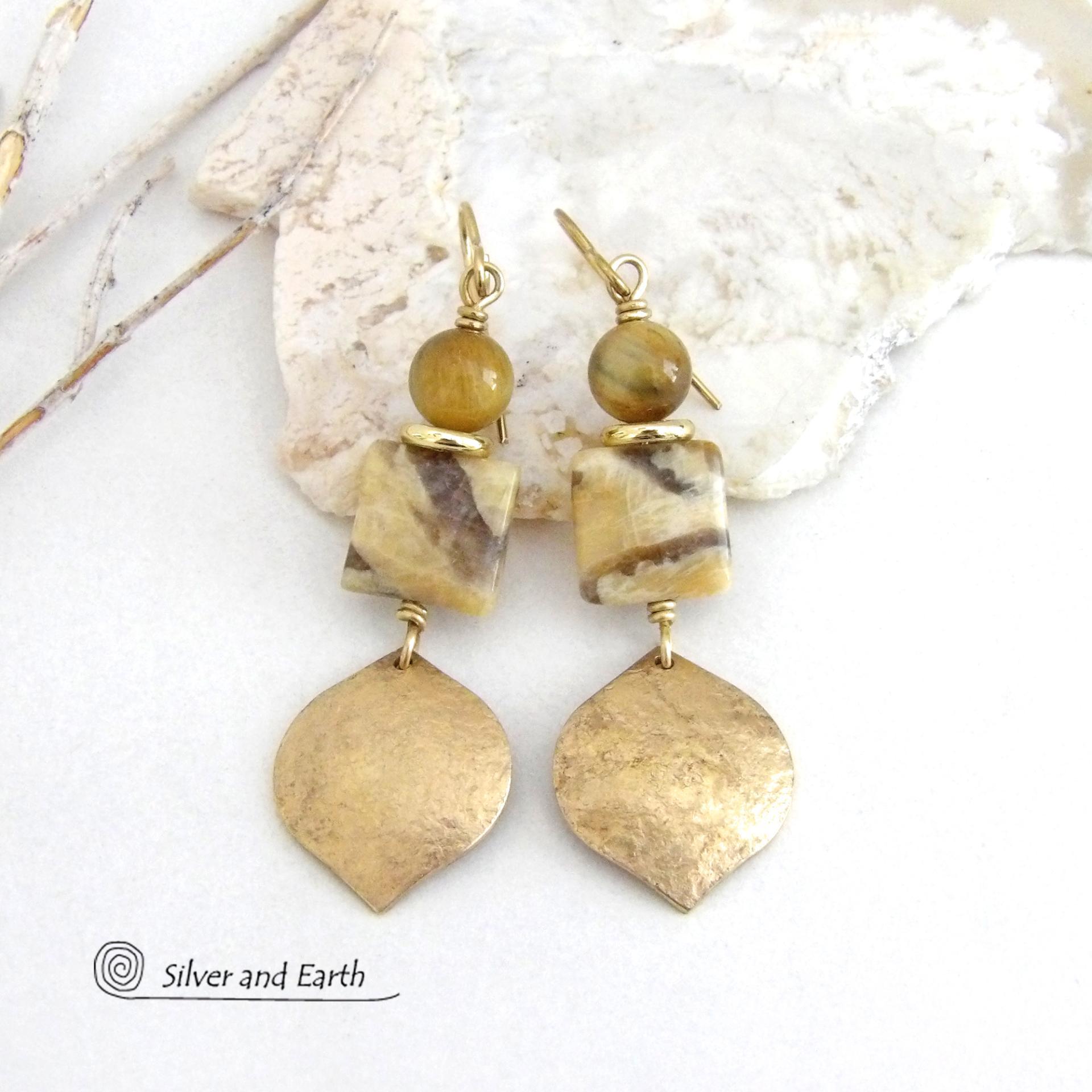 These handcrafted earrings feature shiny gold brass dangles with a hammered raw silk texture accented with graphic feldspar and golden tiger's eye gemstones and shiny brass beads. Graphic feldspar is a type of moonstone that has smoky quartz inclusions which creates unique natural patterns. They have an elegant, modern chic style that looks great dressed up or down. 