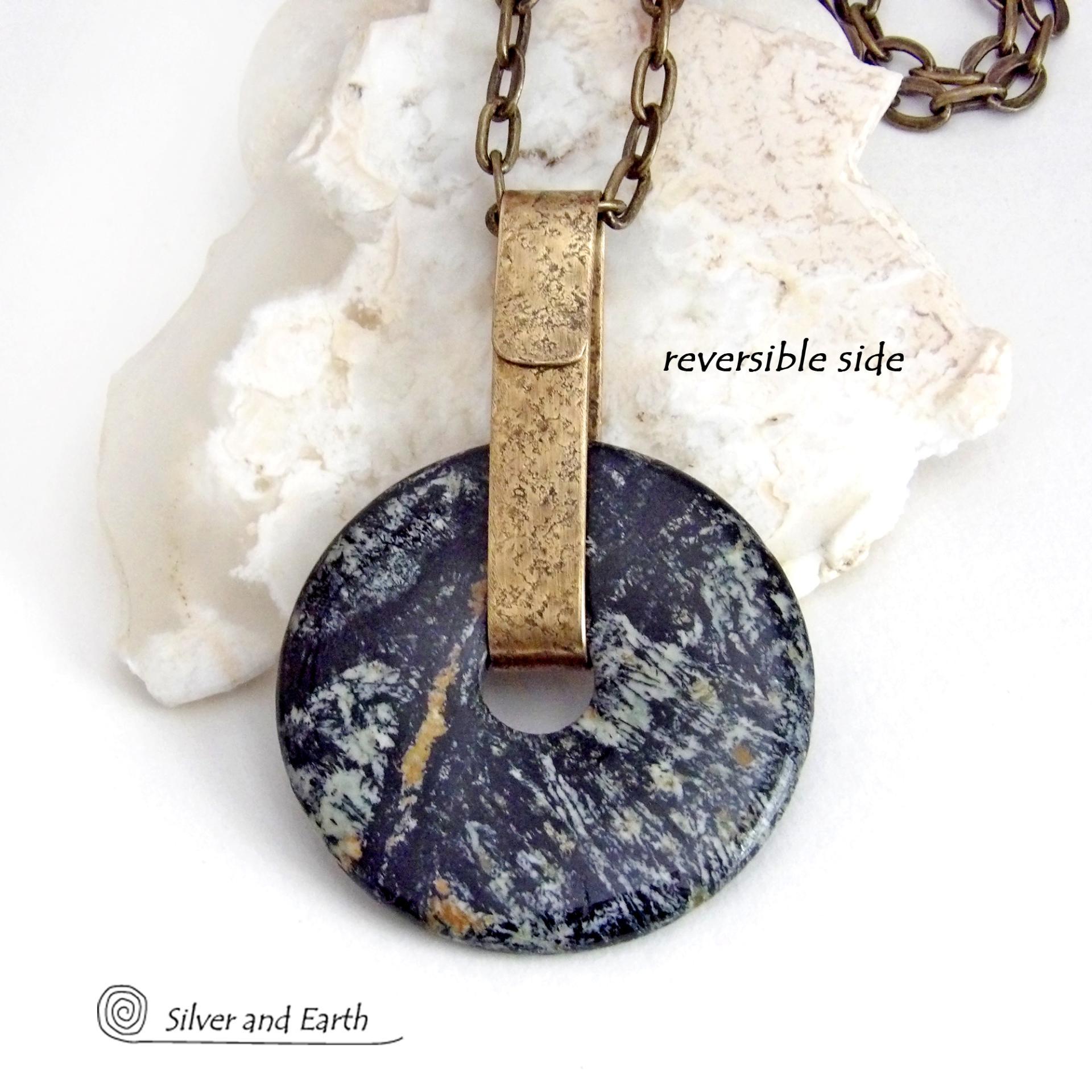 This one-of-a-kind pendant necklace has a large stunning fireworks jasper stone accented with a hand forged gold brass bail. The stone has a natural bold dramatic pattern in hues of black, gold, mint green and cream. The design is modern and bold - yet classic and always in fashion. It can be worn by either a man or women. It's reversible and can be worn on either side. Makes a great gift for a natural stone lover. It comes on a 18" antiqued gold brass chain necklace with lobster claw closure.