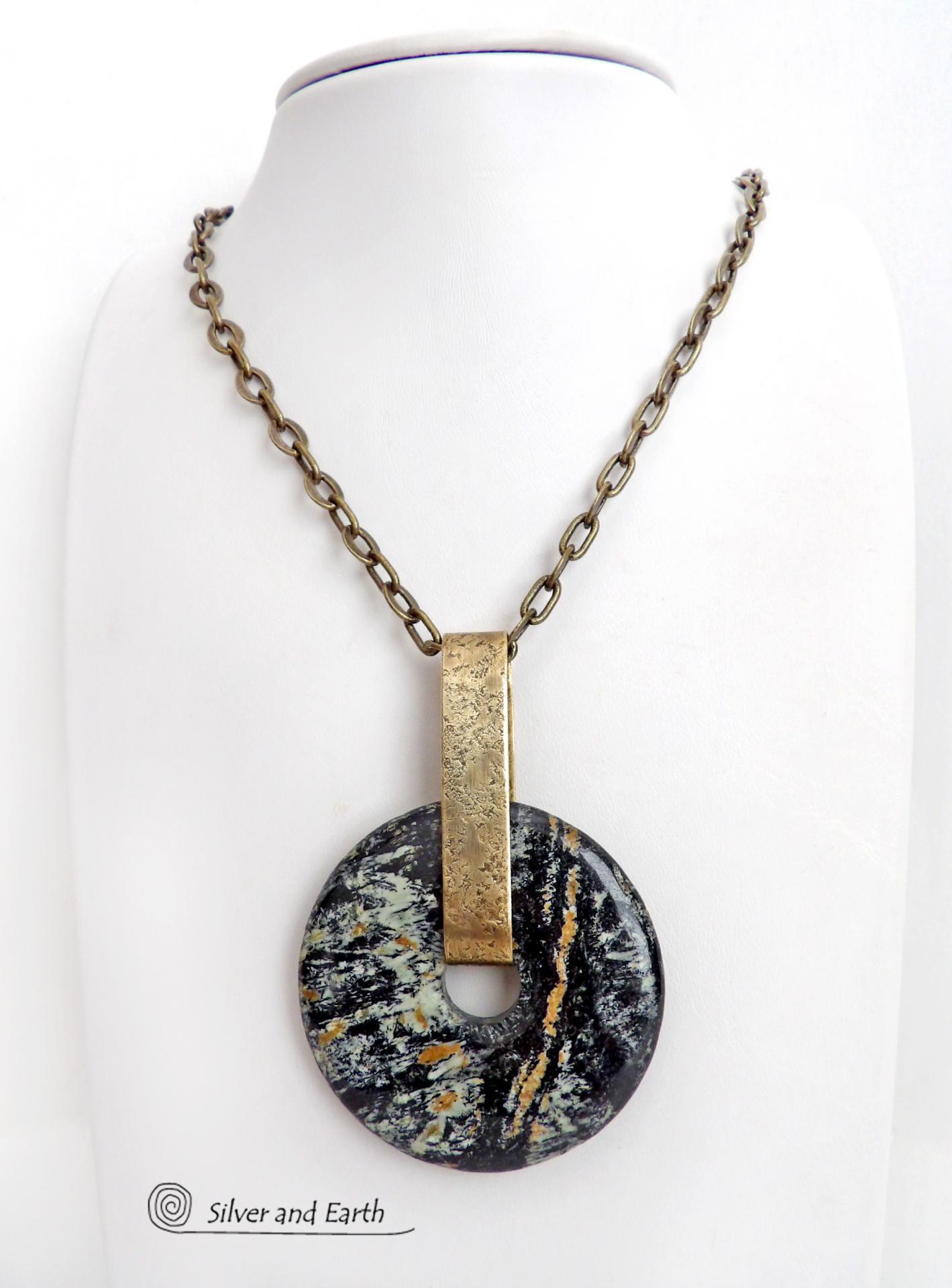 This one-of-a-kind pendant necklace has a large stunning fireworks jasper stone accented with a hand forged gold brass bail. The stone has a natural bold dramatic pattern in hues of black, gold, mint green and cream. The design is modern and bold - yet classic and always in fashion. It can be worn by either a man or women. It's reversible and can be worn on either side. Makes a great gift for a natural stone lover. Handmade in the USA by Silver and Earth Jewelry.