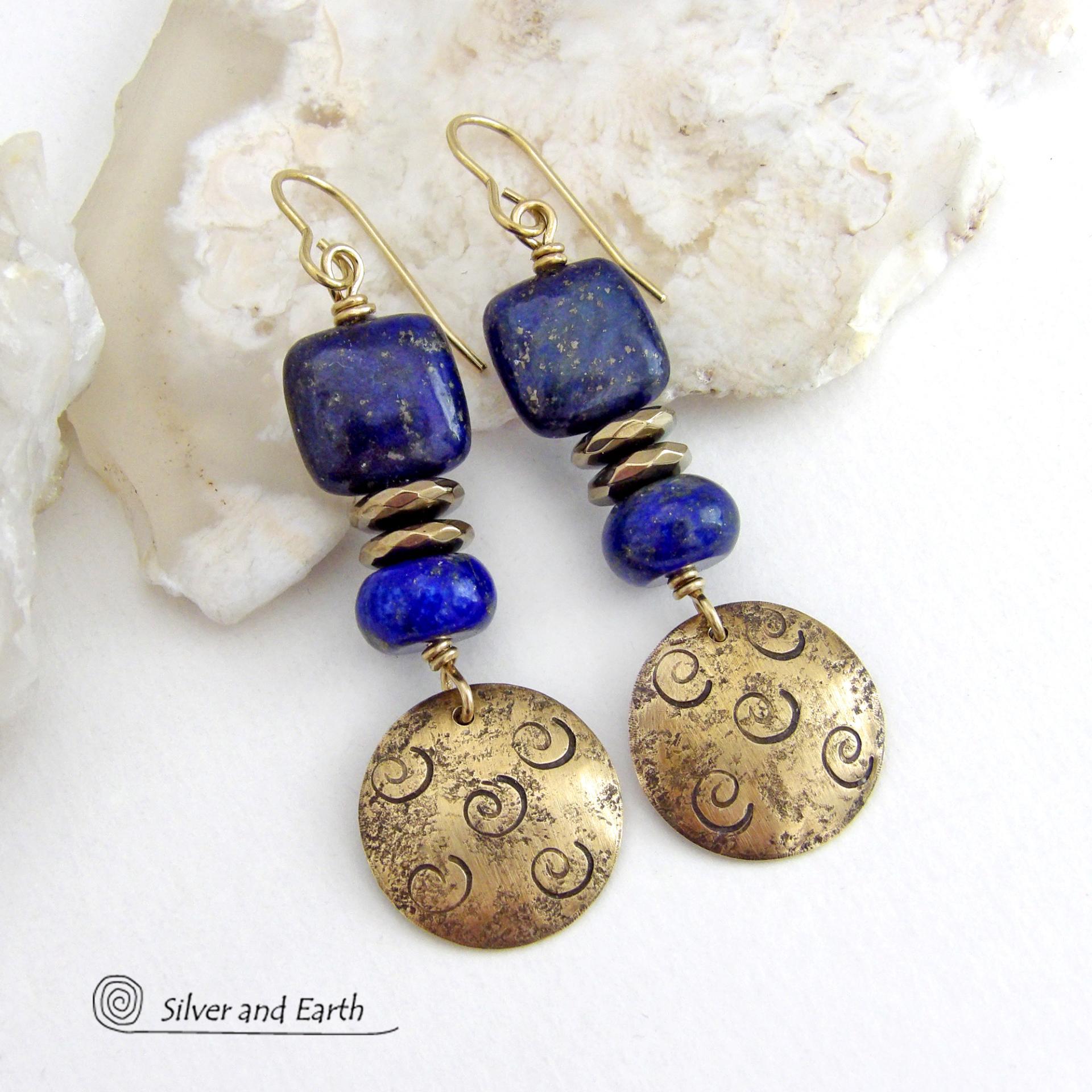 These handcrafted earrings feature round gold brass dangles with a hand stamped spiral texture. They are accented with natural lapis lazuli gemstones and faceted hematite stone beads with an electroplated champagne gold tone finish. The lapis stones are a rich shade of blue, along with natural gold pyrite inclusions. They have a modern chic, elegant style that coordinates beautifully with all wardrobe types - dressed up or down. Perfect for women that love unique artisan handcrafted jewelry