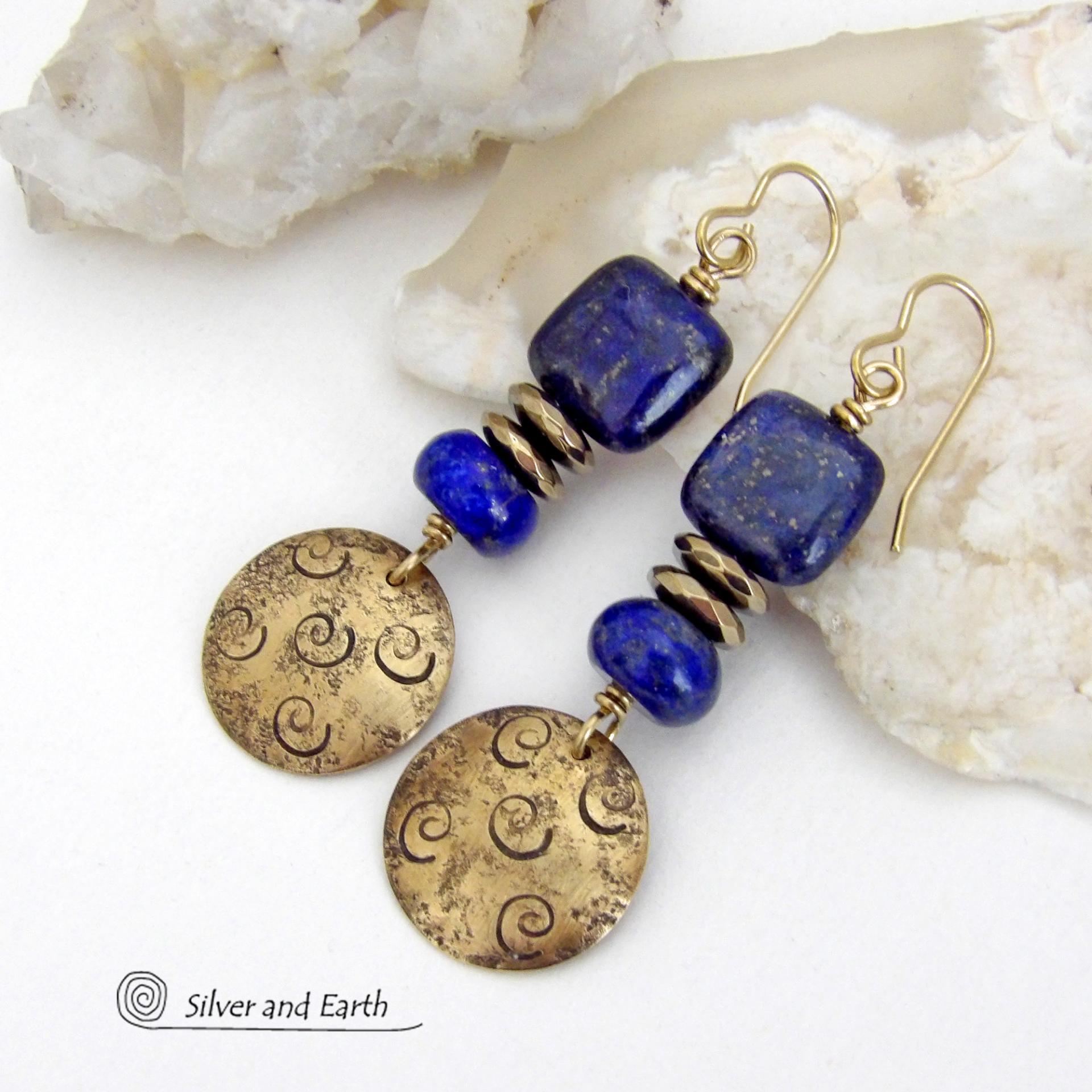 These handcrafted earrings feature round gold brass dangles with a hand stamped spiral texture. They are accented with natural lapis lazuli gemstones and faceted hematite stone beads with an electroplated champagne gold tone finish. The lapis stones are a rich shade of blue, along with natural gold pyrite inclusions. They have a modern chic, elegant style that coordinates beautifully with all wardrobe types - dressed up or down. Perfect for women that love unique artisan handcrafted jewelry