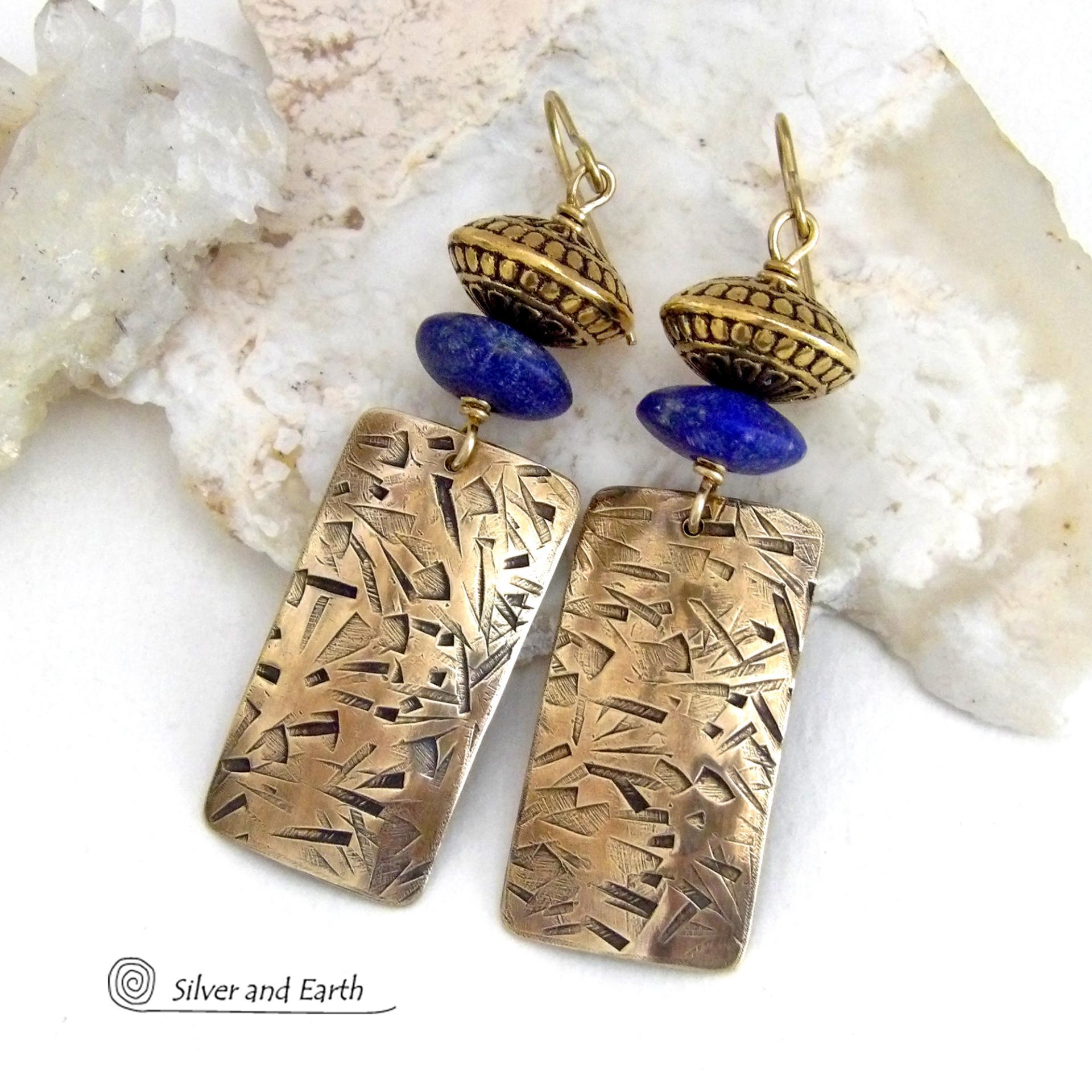 These earrings feature handcrafted brass rectangle dangles with a hand stamped texture accented with matte lapis lazuli gemstones and brass tribal style beads. They have an elegant modern style with boho chic flair that coordinates beautifully with all wardrobe styles. Perfect for women that love to wear unique artisan handcrafted jewelry. Handmade in the USA by Silver and Earth Jewelry.