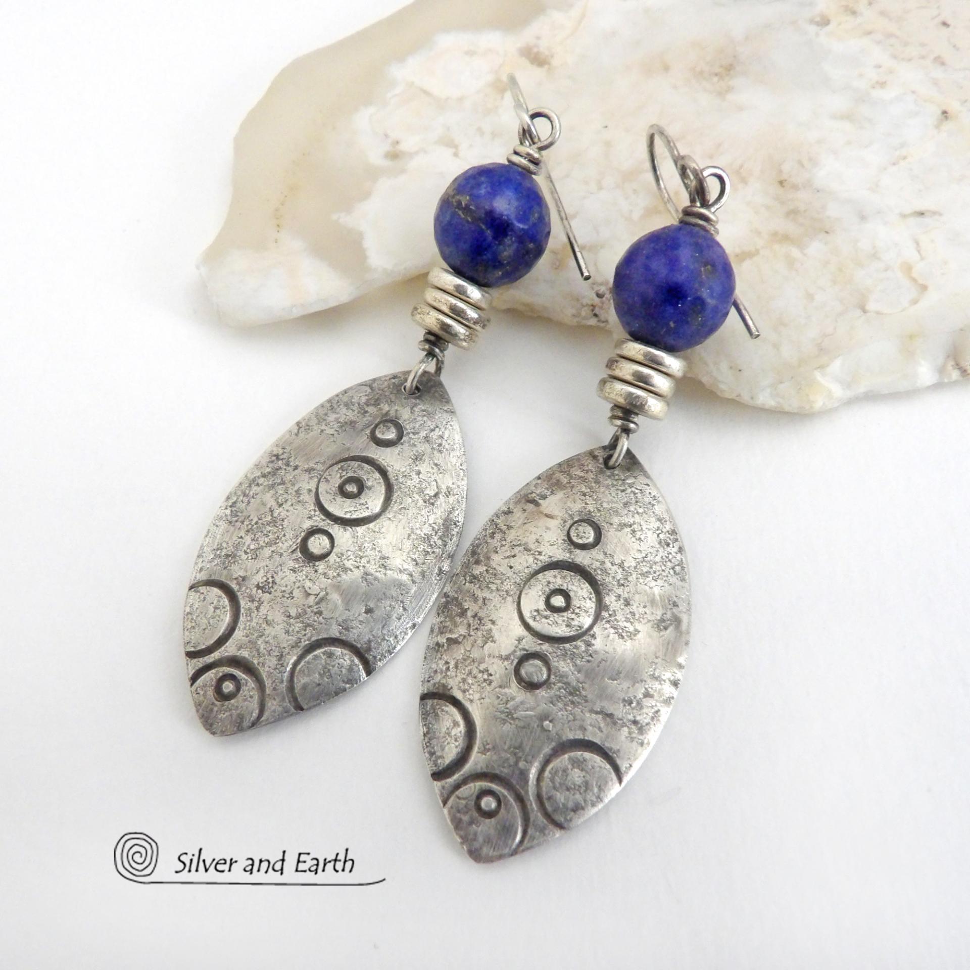 These artisan handcrafted sterling silver earrings have an exotic, Egyptian inspired vibe. The design consists of sterling dangles with a hand stamped texture accented with faceted lapis lazuli gemstones and small pewter beads. Bold and unique - they'll make a striking statement and will add a touch of cultural exotic charm to any outfit.