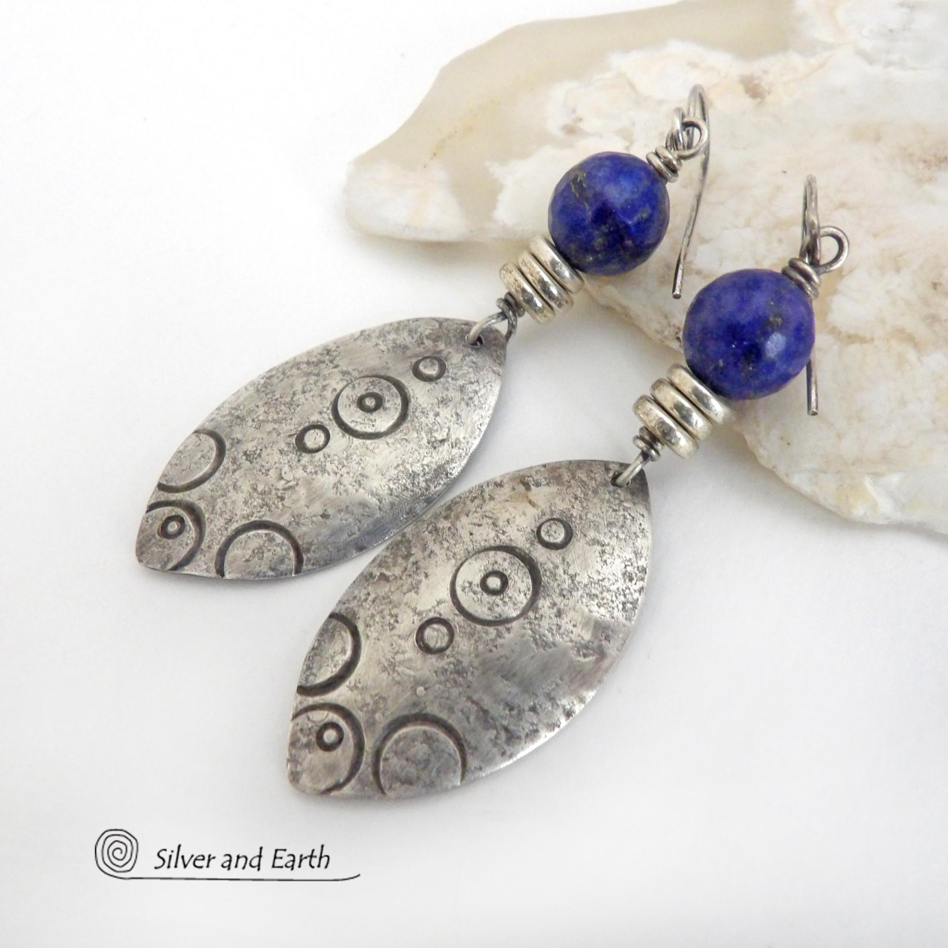  These artisan handcrafted steling silver dangle earrings have a distinct  "Egyptian inspired vibe," evoking the mystique and power of that ancient civilization. The unique design consists of sterling dangles with a hand stamped texture accented with faceted lapis lazuli gemstones. They are perfect for women that like to make a bold, eye-catching statement with their jewelry. 