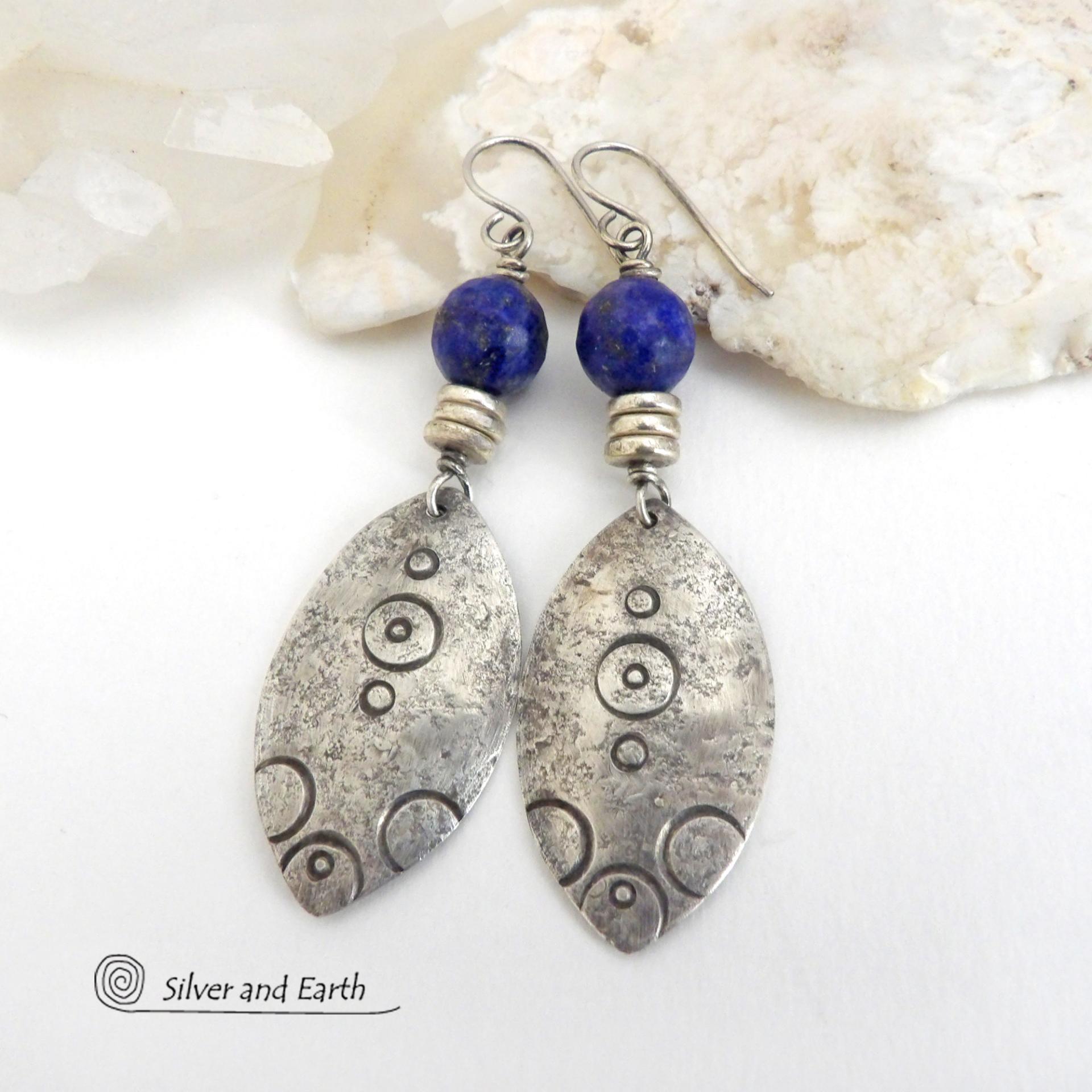  These artisan handcrafted steling silver dangle earrings have a distinct  "Egyptian inspired vibe," evoking the mystique and power of that ancient civilization. The unique design consists of sterling dangles with a hand stamped texture accented with faceted lapis lazuli gemstones. They are perfect for women that like to make a bold, eye-catching statement with their jewelry. 
