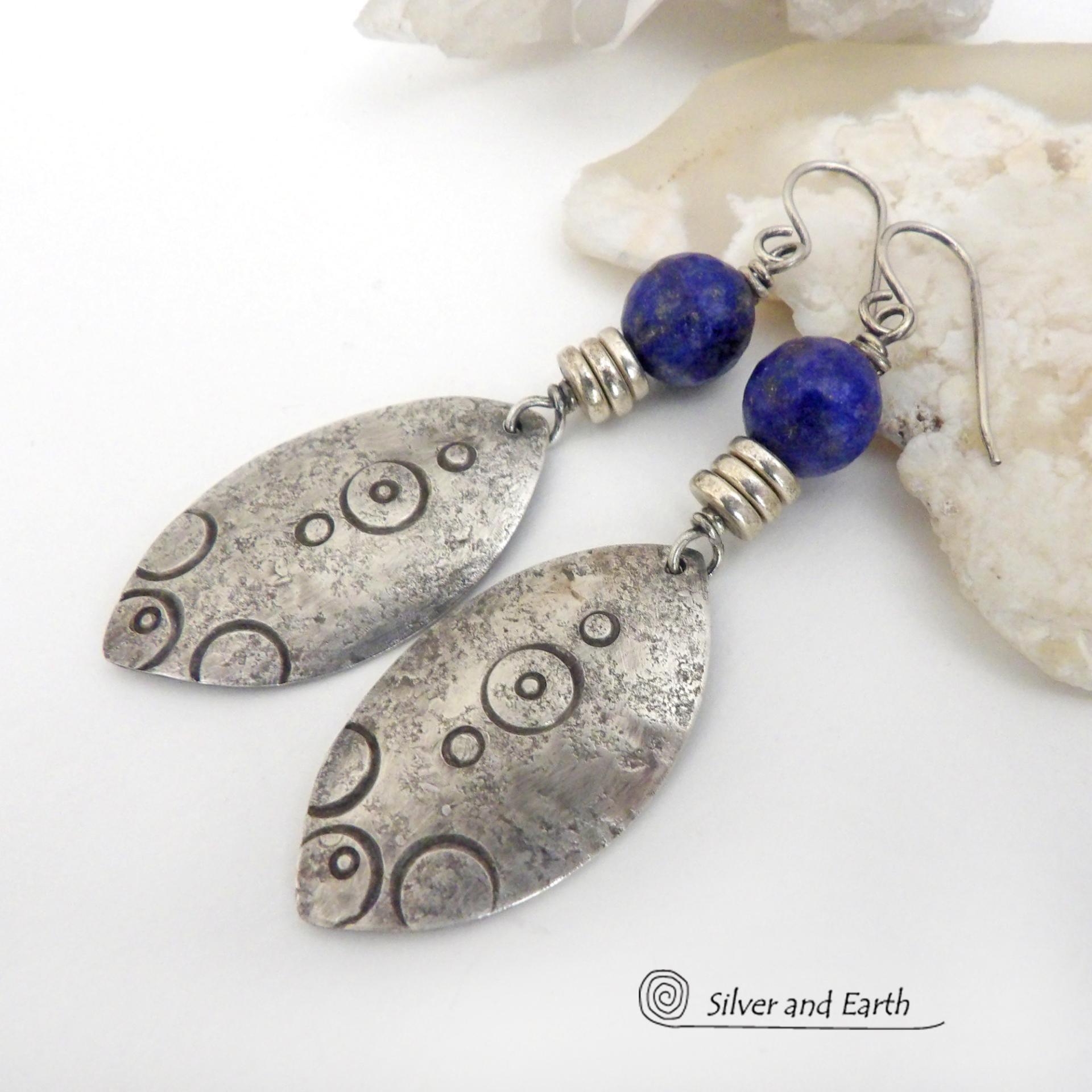  These artisan handcrafted steling silver dangle earrings have a distinct  "Egyptian inspired vibe," evoking the mystique and power of that ancient civilization. The unique design consists of sterling dangles with a hand stamped texture accented with faceted lapis lazuli gemstones. They are perfect for women that like to make a bold, eye-catching statement with their jewelry. 