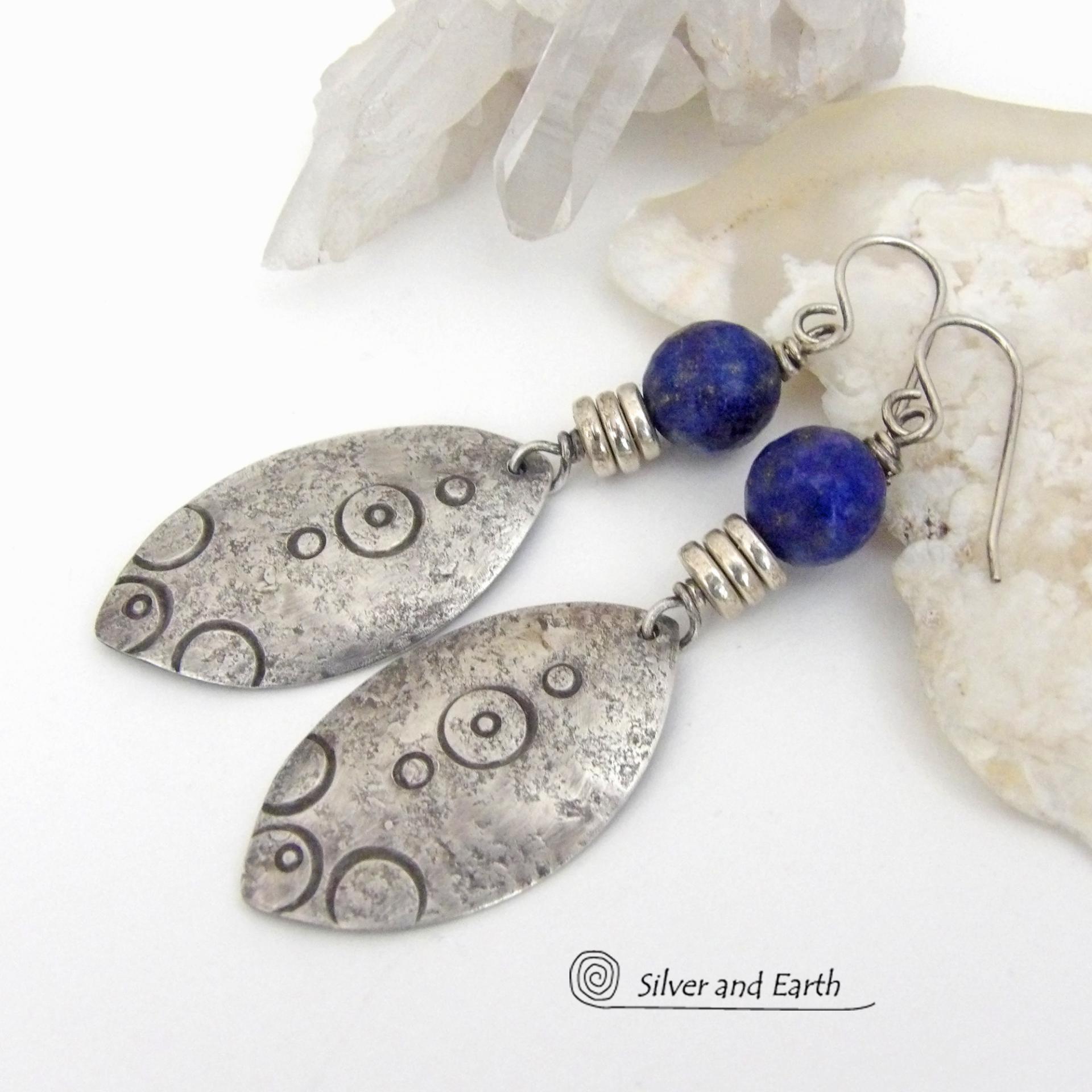  These artisan handcrafted steling silver dangle earrings have a distinct  "Egyptian inspired vibe," evoking the mystique and power of that ancient civilization. The unique design consists of sterling dangles with a hand stamped texture accented with faceted lapis lazuli gemstones. They are perfect for women that like to make a bold, eye-catching statement with their jewelry. 