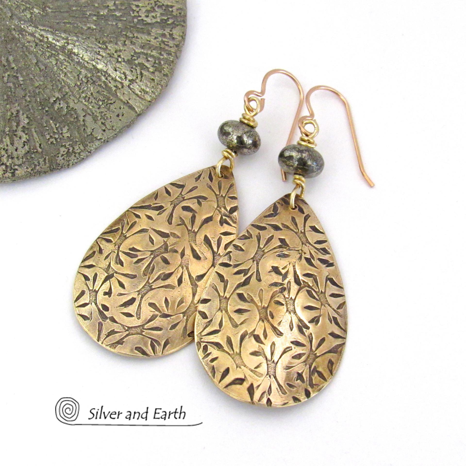 These handcrafted gold brass teardrop earrings have a hand stamped texture and are accented with natural silver pyrite gemstone beads. They have a modern contemporary style that coordinates beautifully with all wardrobe types.  MEASUREMENTS: Total length: 2-3/8” from top of bronze ear wires and 1” at widest point. Created out of solid gold brass; the shapes were hand stamped for texture; oxidized to enhance the detail. Handmade in the USA by Silver and Earth Jewelry.