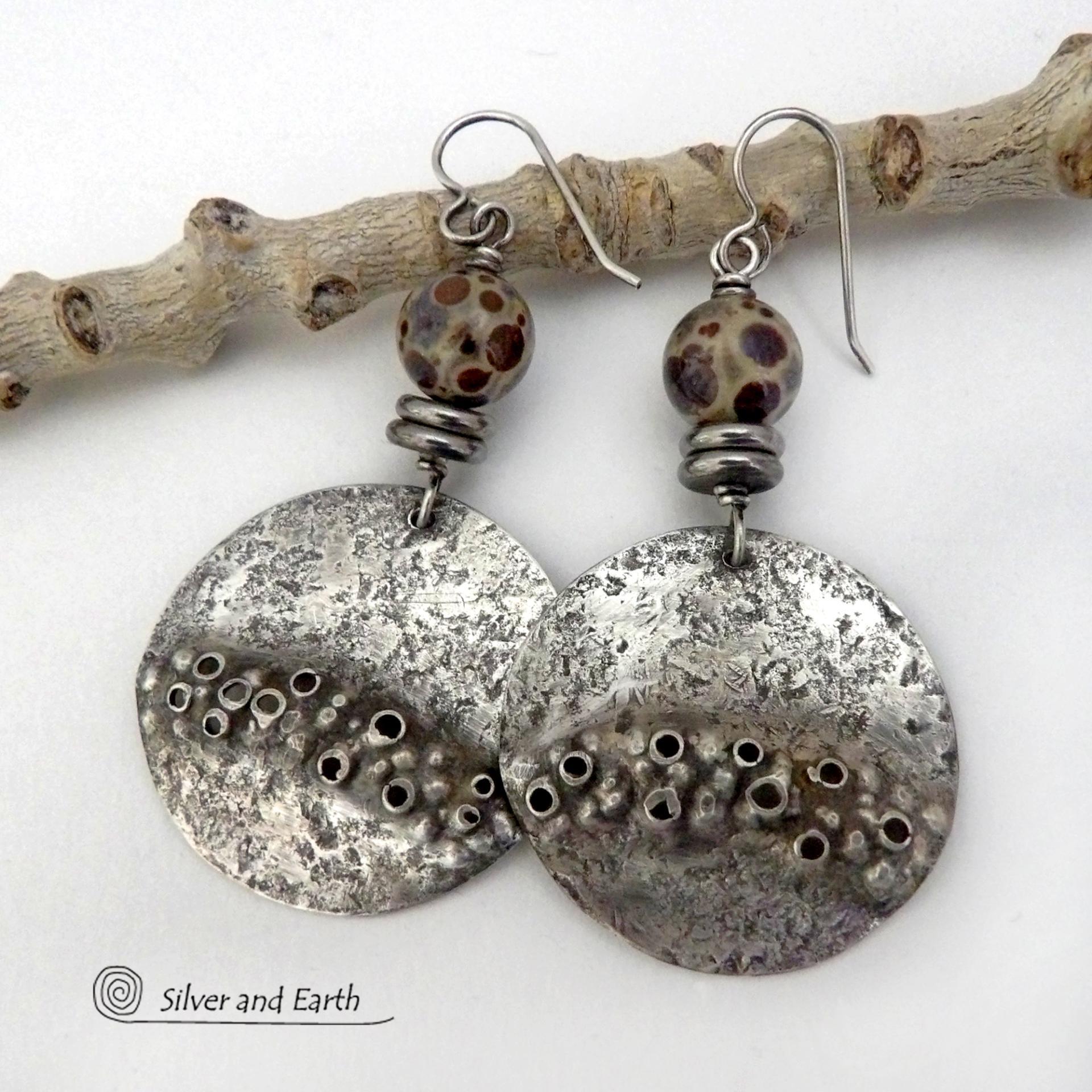 Unique and one-of-a-kind, these handcrafted large sterling silver earrings have a bold edgy vibe. They feature rustic hammered sterling silver accented with natural asteroid jasper stones and stainless steel beads. This type of stone is known for its unique dotted matrix in earth-tone hues of brown, gray and tan. It's also known as chocolate ocean jasper because it's found on the shores of Madagascar where ocean jasper is also found. Bold and striking - they're sure to make a unique statement.