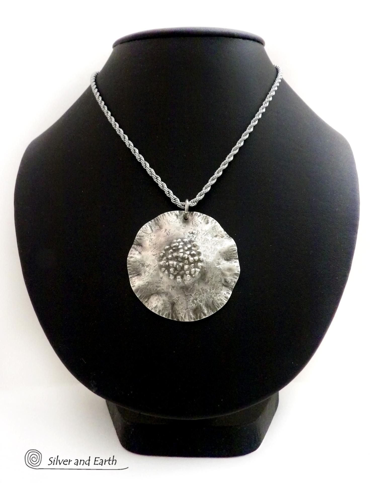 This handcrafted sterling silver necklace has a modern, earthy organic vibe. Perfect for everyday wear - it goes with everything. It features a large sterling silver circle with a rustic, hand forged texture and crimped ruffled edges.  Big and bold, it's sure to make an eye-catching statement. Handmade in the USA by Silver and Earth, a New Mexico True Certified business.  