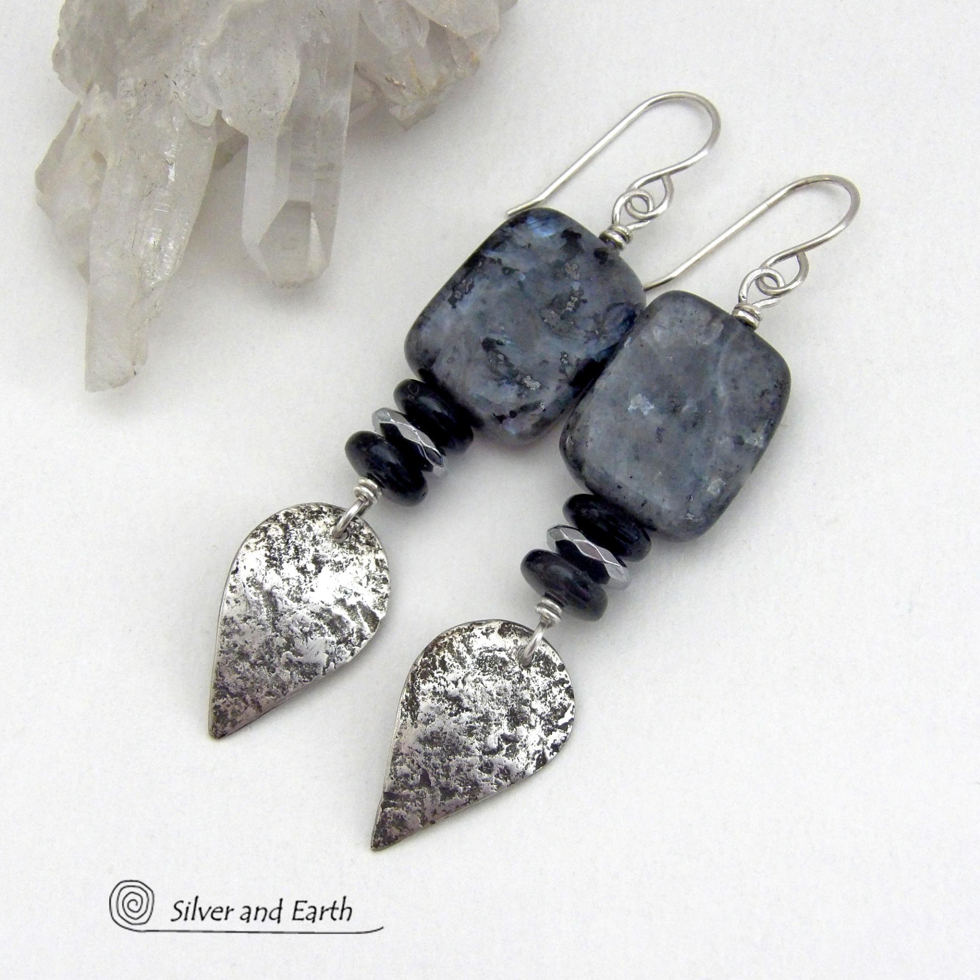 These handcrafted sterling silver earrings feature natural larvikite gemstones accented with small sterling silver dangles, black onyx and faceted silver hematite gemstones. The larvikite has a pearly, grayish black hue with iridescent flashes of light which cast off a natural shimmer & shine. They have a modern, chic contemporary style that will look great dressed up or down. Larvikite originates from the Larvik region in Norway. It's also called Norwegian moonstone and black labradorite.