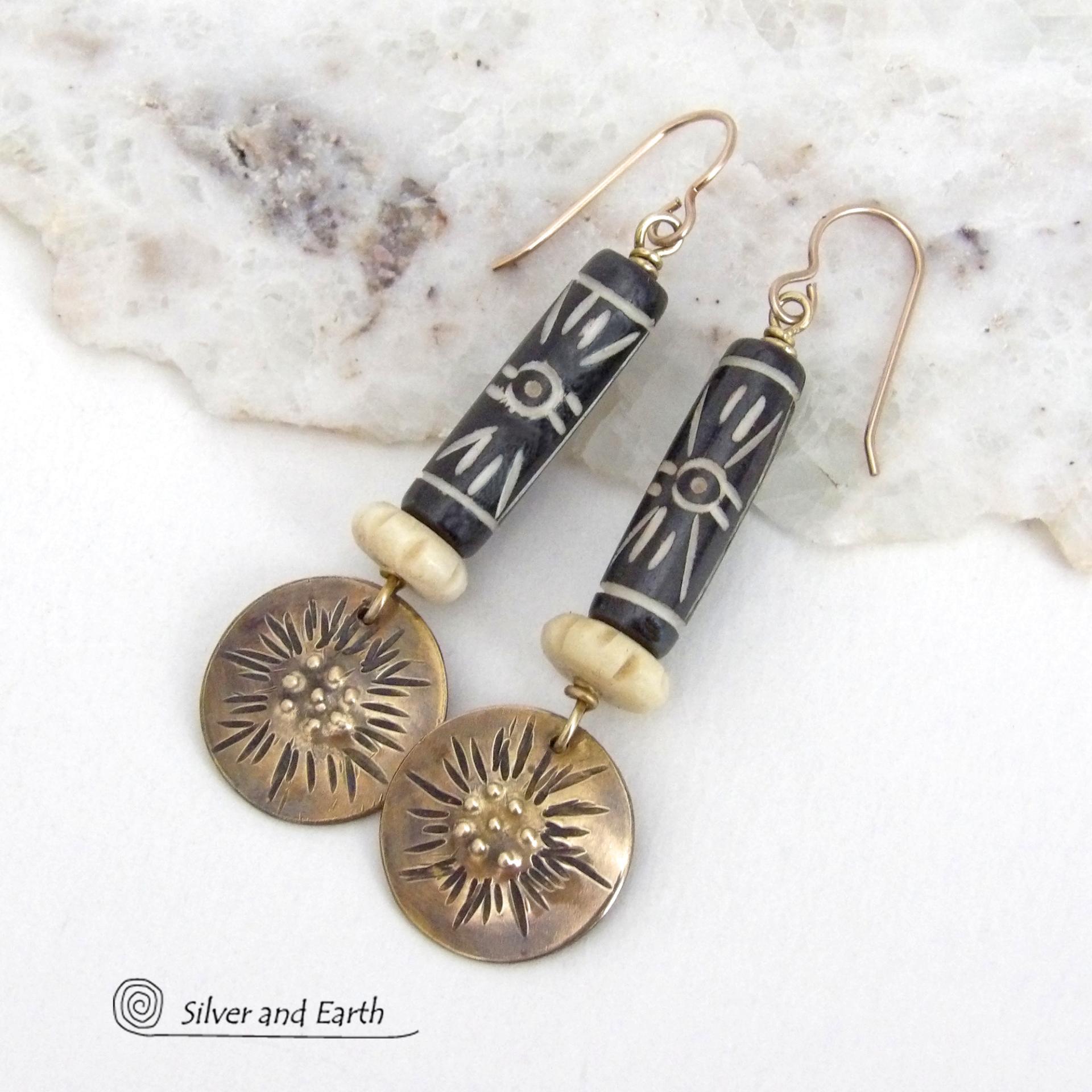 These handcrafted earrings feature African batik carved bone beads accented with textured gold brass dangles and carved bone beads. They have a boho chic tribal flair that will make a striking statement. Perfect for women that love to wear bold unique jewelry. Handmade in the USA by Silver and Earth Jewelry. 