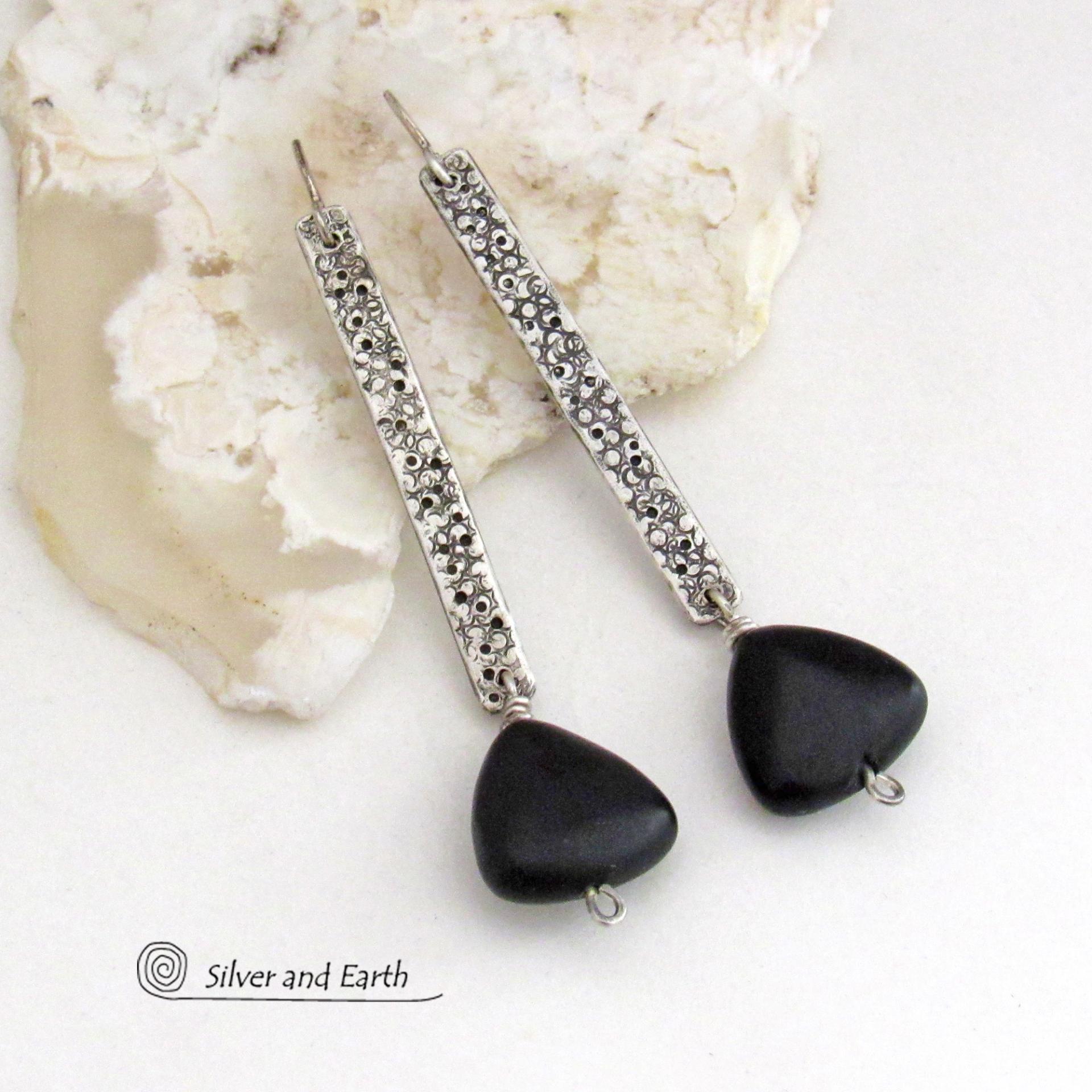 These handcrafted earrings feature long textured skinny strips of sterling silver accented with triangular-shaped black onyx stones with a matte finish. They have a contemporary modern style with a bold, edgy vibe.