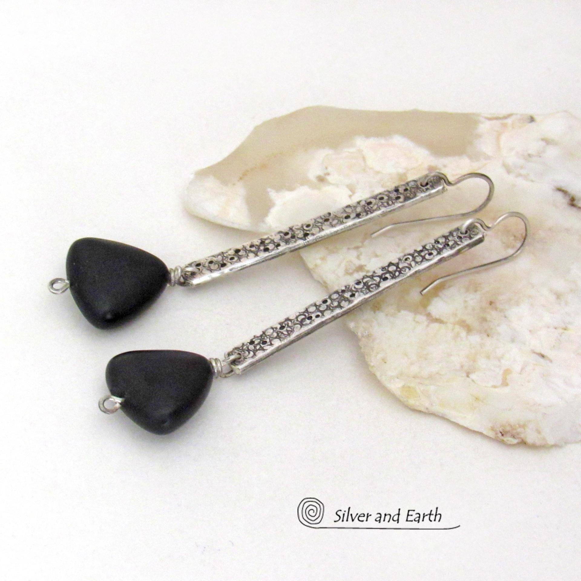 These handcrafted earrings feature long textured skinny strips of sterling silver accented with triangular-shaped black onyx stones with a matte finish. They have a contemporary modern style with a bold, edgy vibe.
