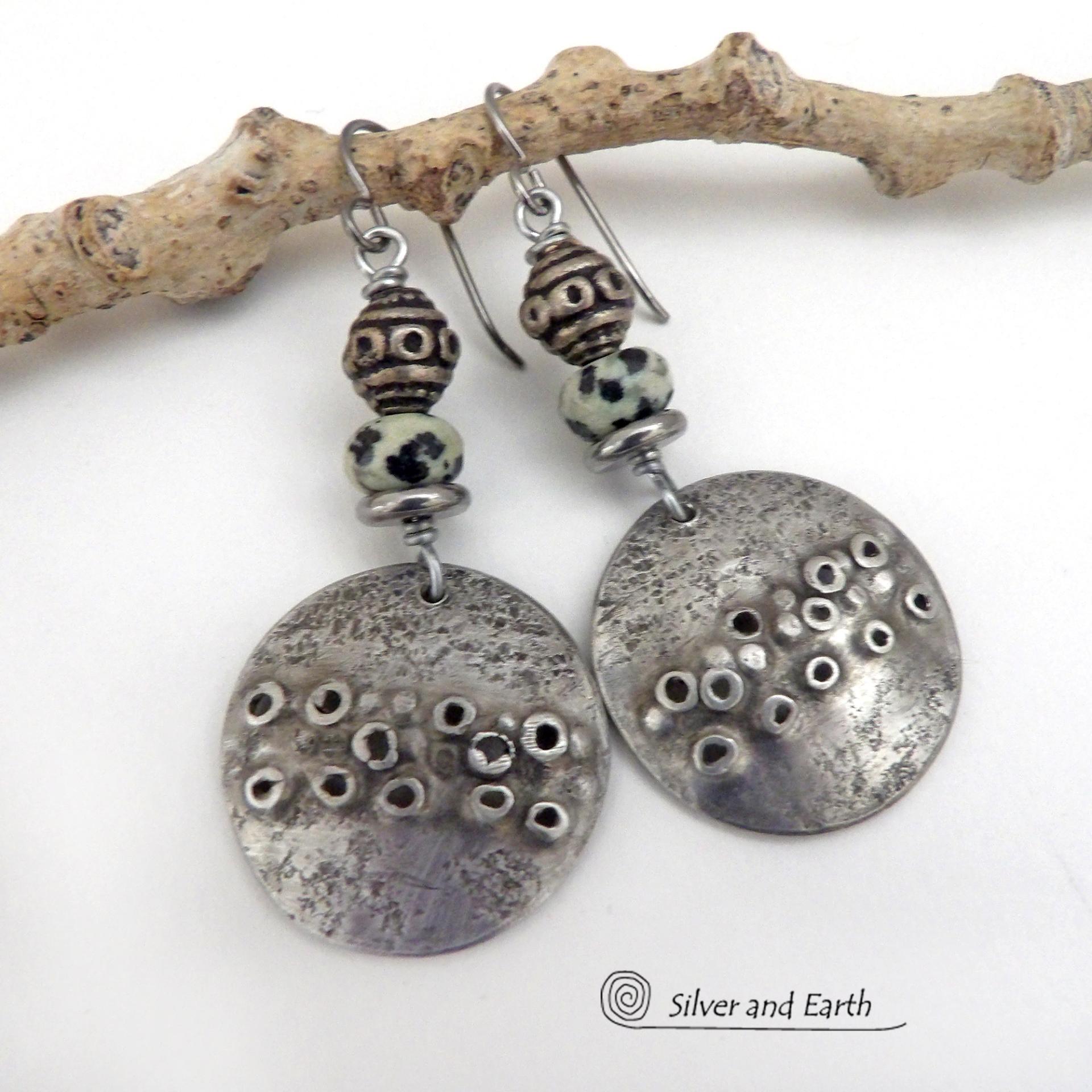 These handcrafted silver pewter earrings have a rustic, hand textured design and are accented with natural dalmatian jasper gemstones, stainless steel and vintage silver tone metal beads. They have an earthy, edgy organic style that makes a unique statement.This type of jasper is known for its spotted pattern that resembles the Dalmatian breed of dog. The matrix consists of mineral inclusions of brown iron oxide, black tourmaline & other minerals which create the natural "spots" in the stone. Handmade in th