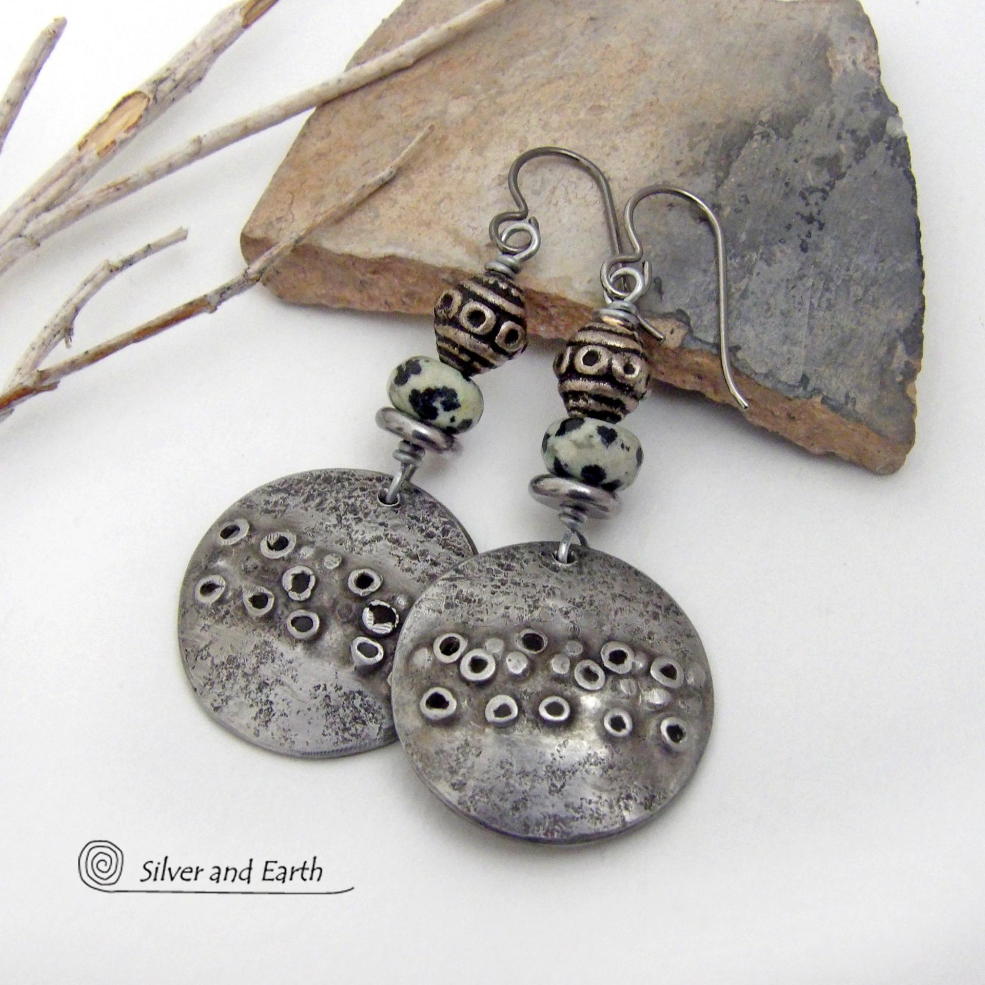 These handcrafted silver pewter earrings have a rustic, hand textured design and are accented with natural dalmatian jasper gemstones, stainless steel and vintage silver tone metal beads. They have an earthy, edgy organic style that makes a unique statement.This type of jasper is known for its spotted pattern that resembles the Dalmatian breed of dog. The matrix consists of mineral inclusions of brown iron oxide, black tourmaline & other minerals which create the natural "spots" in the stone. Handmade in th