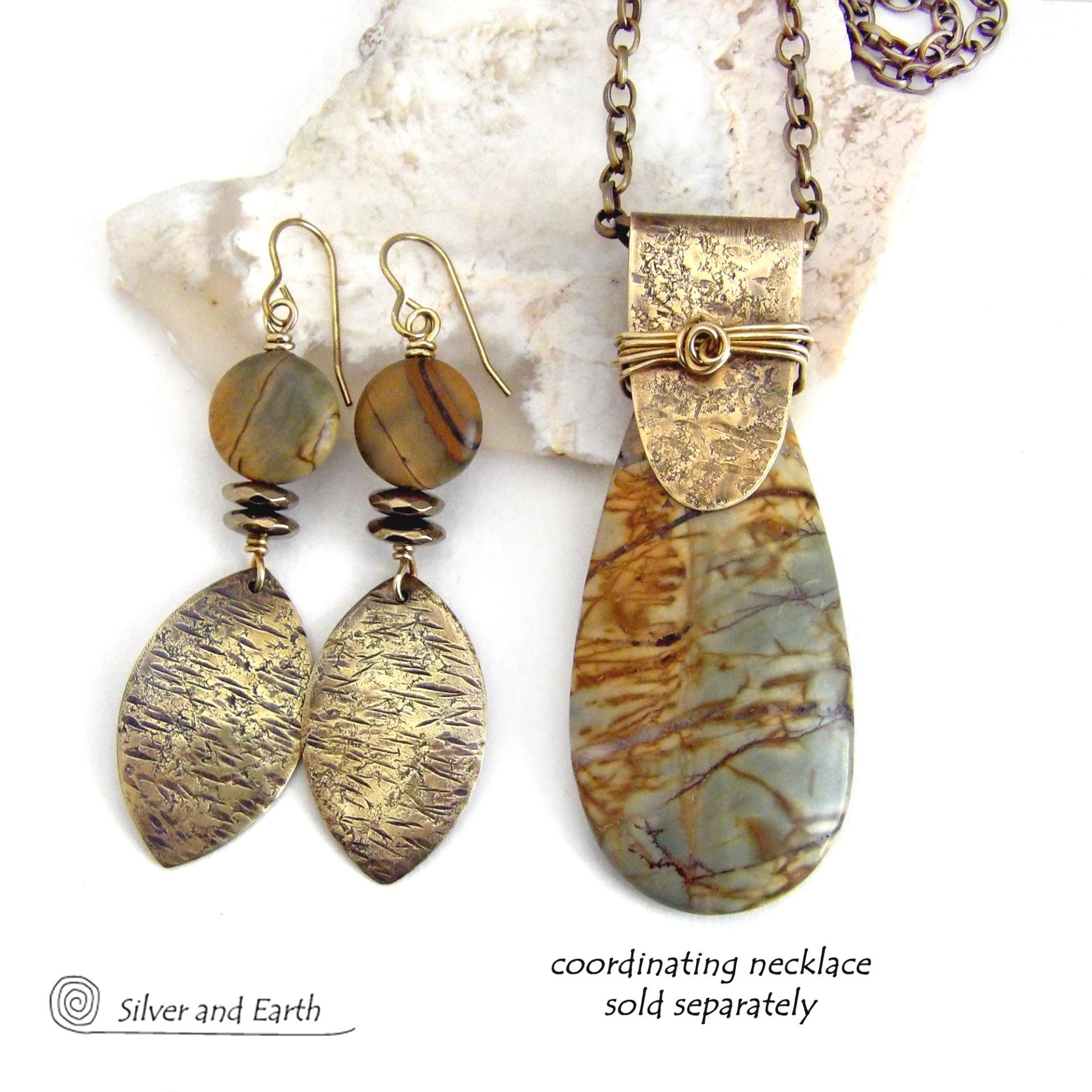 These handcrafted earrings feature textured gold brass dangles accented with natural Picasso jasper gemstones and hematite stone beads. The beads have an electroplated champagne gold tone finish which adds a touch of shimmer and shine. They have an earthy modern style that coordinates well with all wardrobe styles. Coordinating necklace is available and sold separately.