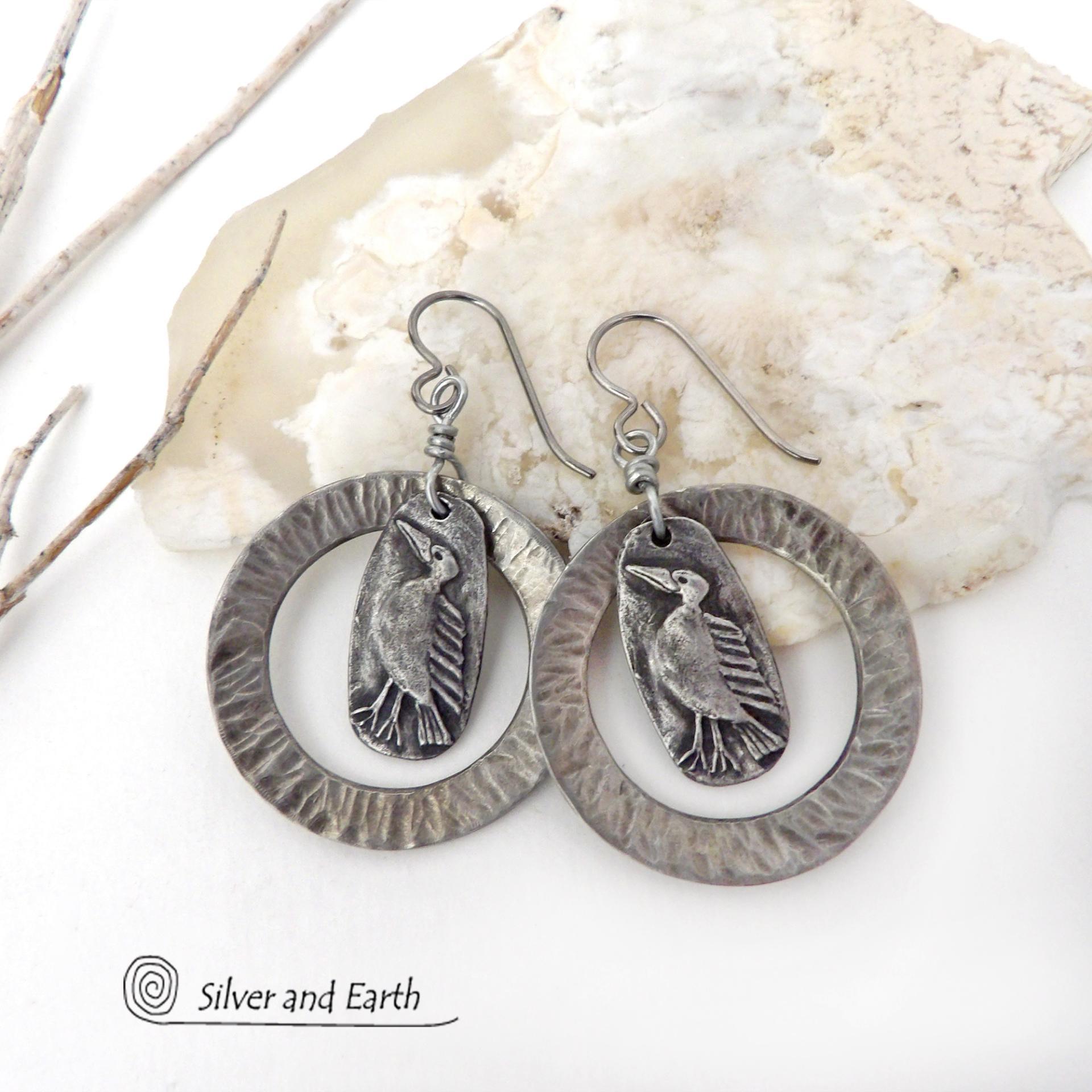 These handcrafted earrings feature silver pewter circle hoops with a hammered texture accented with silver pewter bird charms dangling in front. Lightweight and comfortable to wear, they have a casual earthy style with rustic flair that coordinates with all wardrobe types. They'll make a great gift for a nature / bird lover - or a unique addition to your own jewelry wardrobe. Handmade in the USA by Silver and Earth Jewelry.