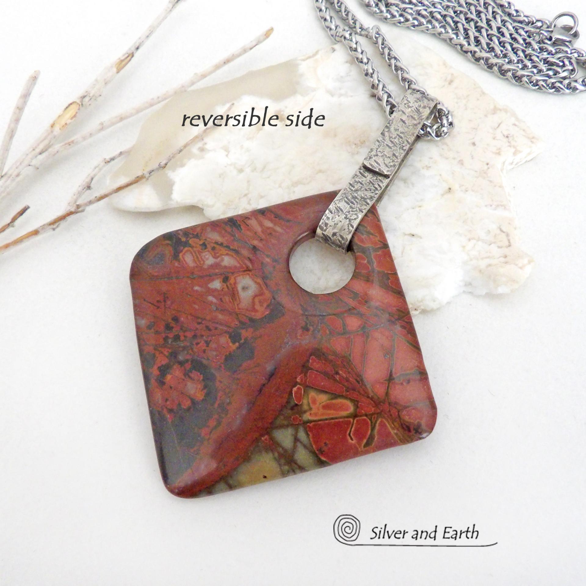 This artisan handcrafted one-of-a-kind necklace features a natural red creek jasper stone accented with a hand forged sterling silver bail with a lightly hammered texture. The stone has a beautiful natural pattern in earthy hues of mossy greens, brick red, brown and orange. It's reversible and can be worn on either side. (See all photos for alternate sides). It makes a great gift for anyone that loves earthy colors and natural stones. The design is unisex so it could be worn by a man or woman.