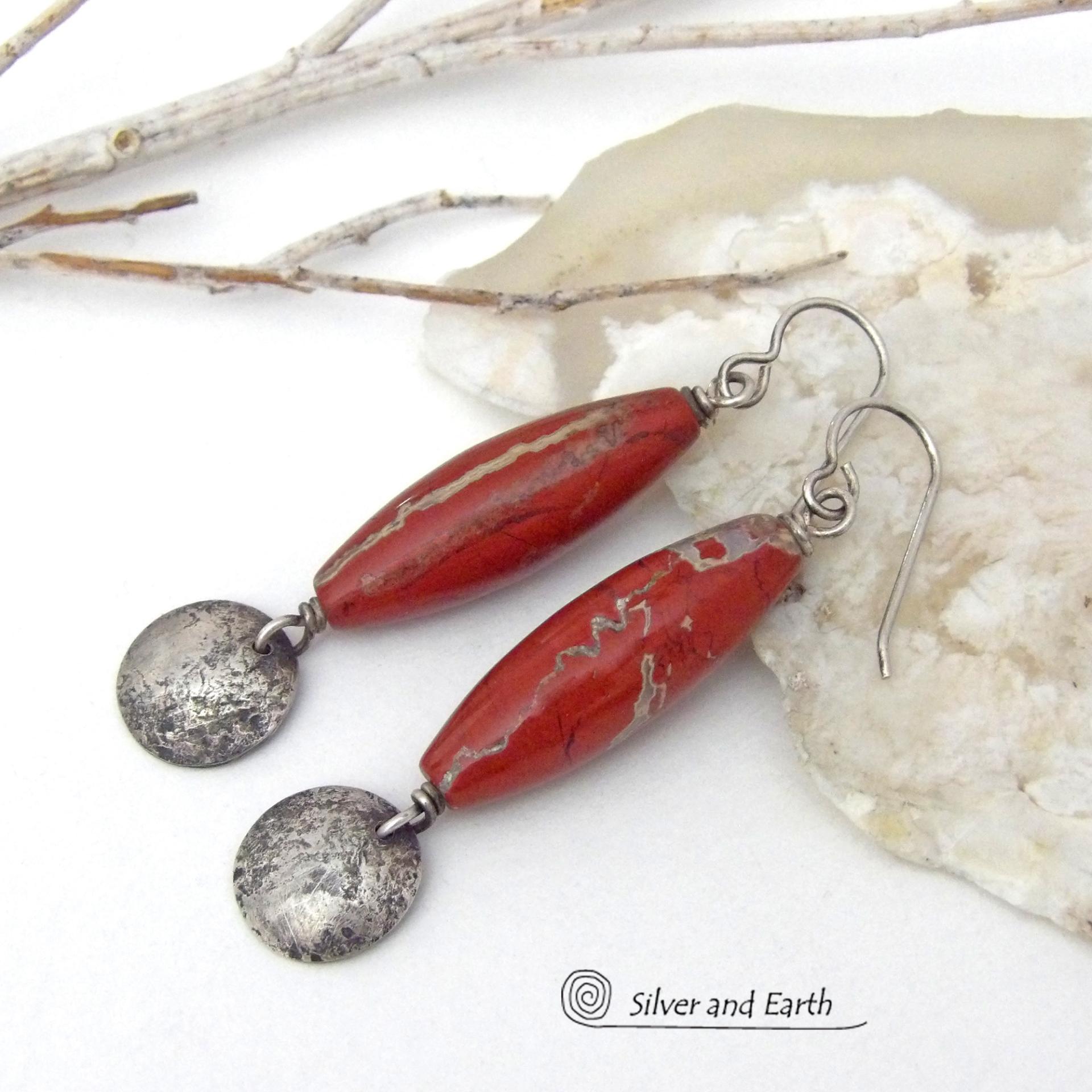 These handmade earrings feature natural red jasper gemstones accented with small hammered sterling silver dangles. The stones have a brick red hue with an interesting matrix of beige streaks and squiggly lines. They have a modern, earthy appeal that coordinates well with all wardrobe styles. They'll make a great gift for a natural stone lover - or a nice addition to your own jewelry wardrobe. They have a coordinating necklace which is sold separately. Handmade in the USA by Silver and Earth Jewelry.  