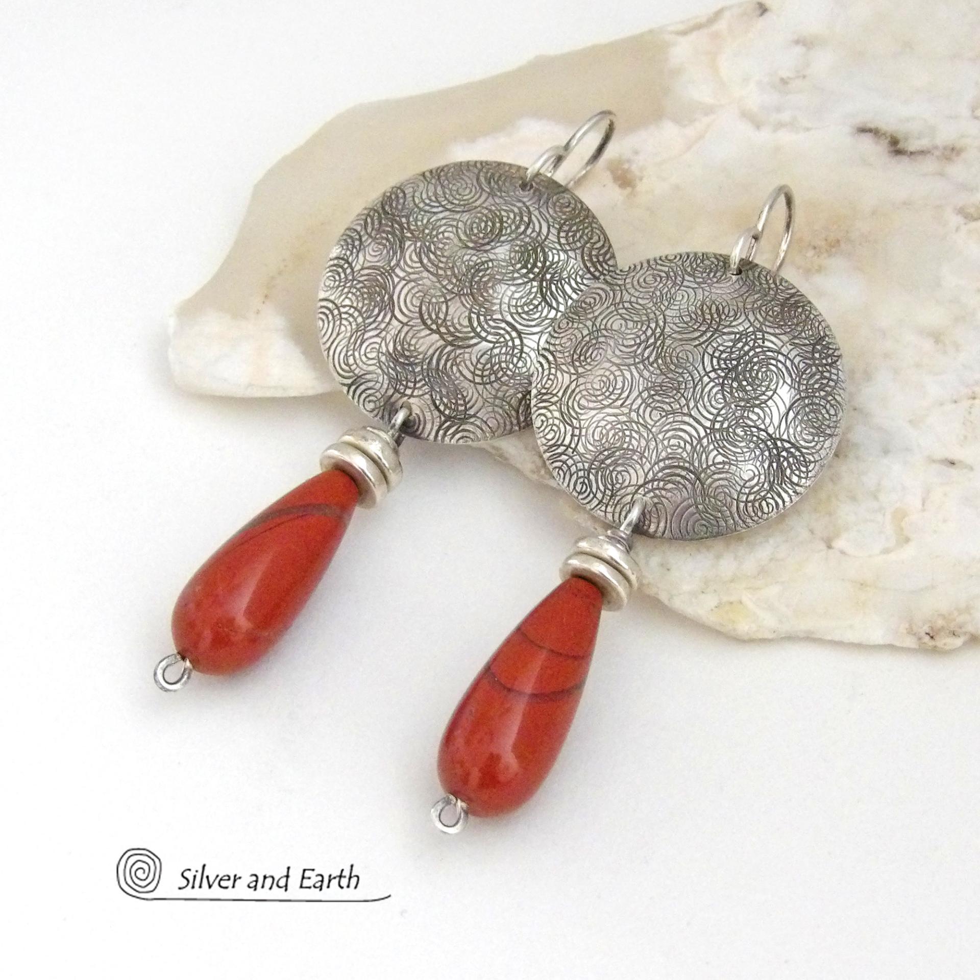 These handcrafted sterling silver earrings have a hand stamped texture and feature slender teardrop-shaped red jasper gemstones dangling from the bottom. The stones are a beautiful shade of burnt red with subtle natural black inclusions. The design is modern, contemporary, classic and always in fashion. 