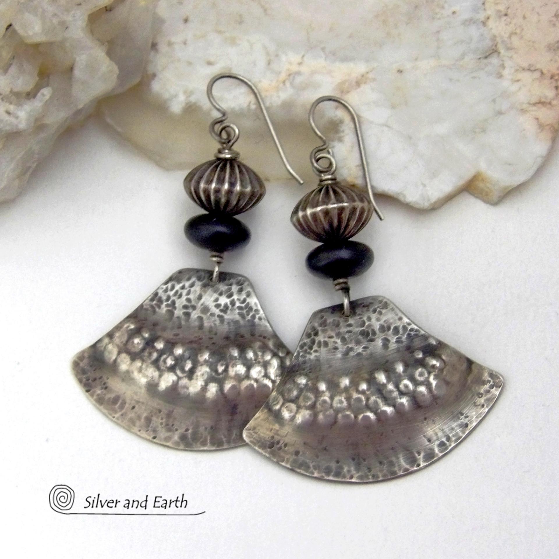 These handcrafted sterling silver earrings have a modern southwestern flair. The sterling shapes have a hammered and stamped texture with an oxidized finish. They are accented with Native Navajo pearl style oxidized sterling silver beads with a rich, corrugated texture and matte black glass beads. Unique and striking, they'll make a bold statement. Handmade in the USA by Silver and Earth Jewelry.