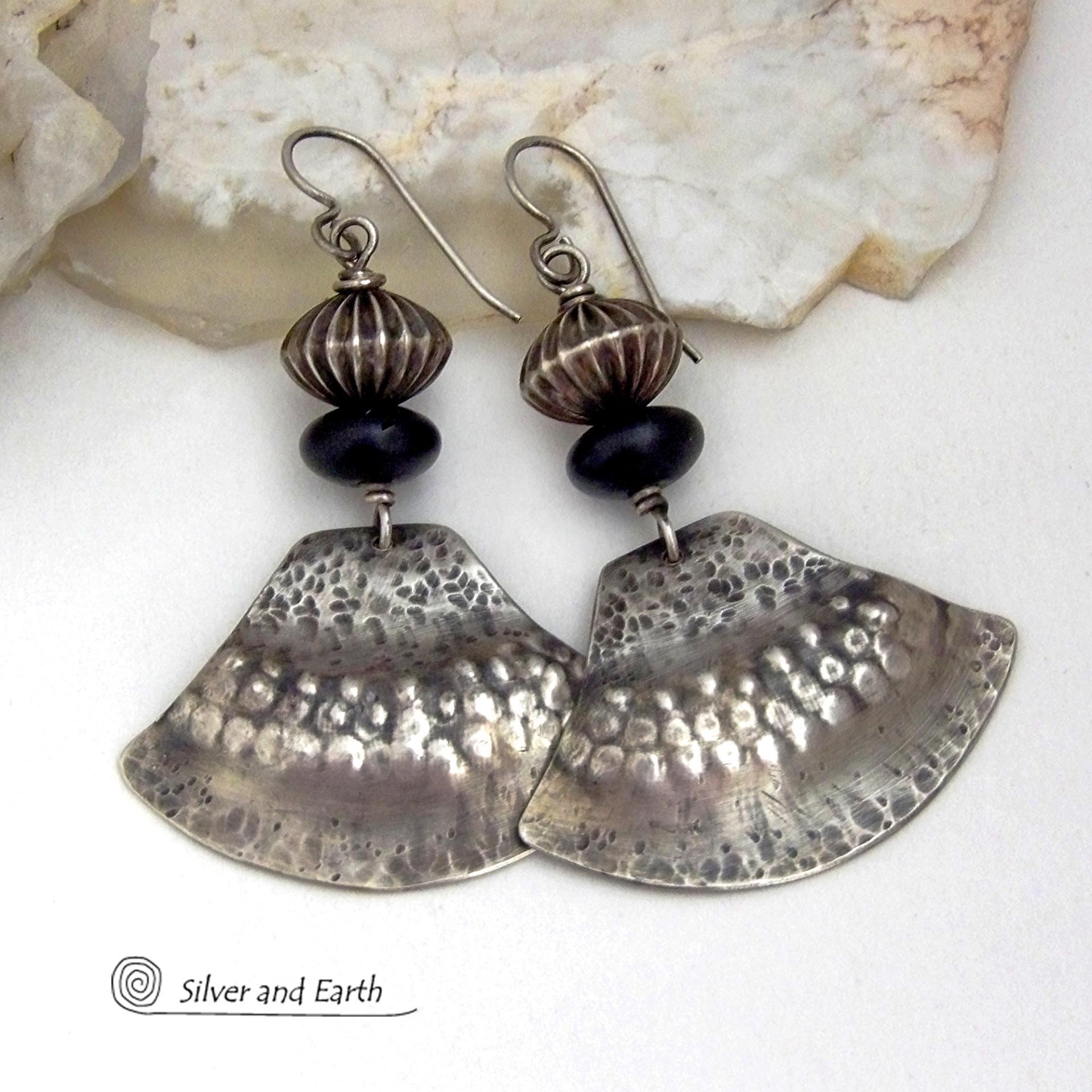 These handcrafted sterling silver earrings have a modern southwestern flair. The sterling shapes have a hammered and stamped texture with an oxidized finish. They are accented with Native Navajo pearl style oxidized sterling silver beads with a rich, corrugated texture and matte black glass beads. Unique and striking, they'll make a bold statement. Handmade in the USA by Silver and Earth Jewelry.