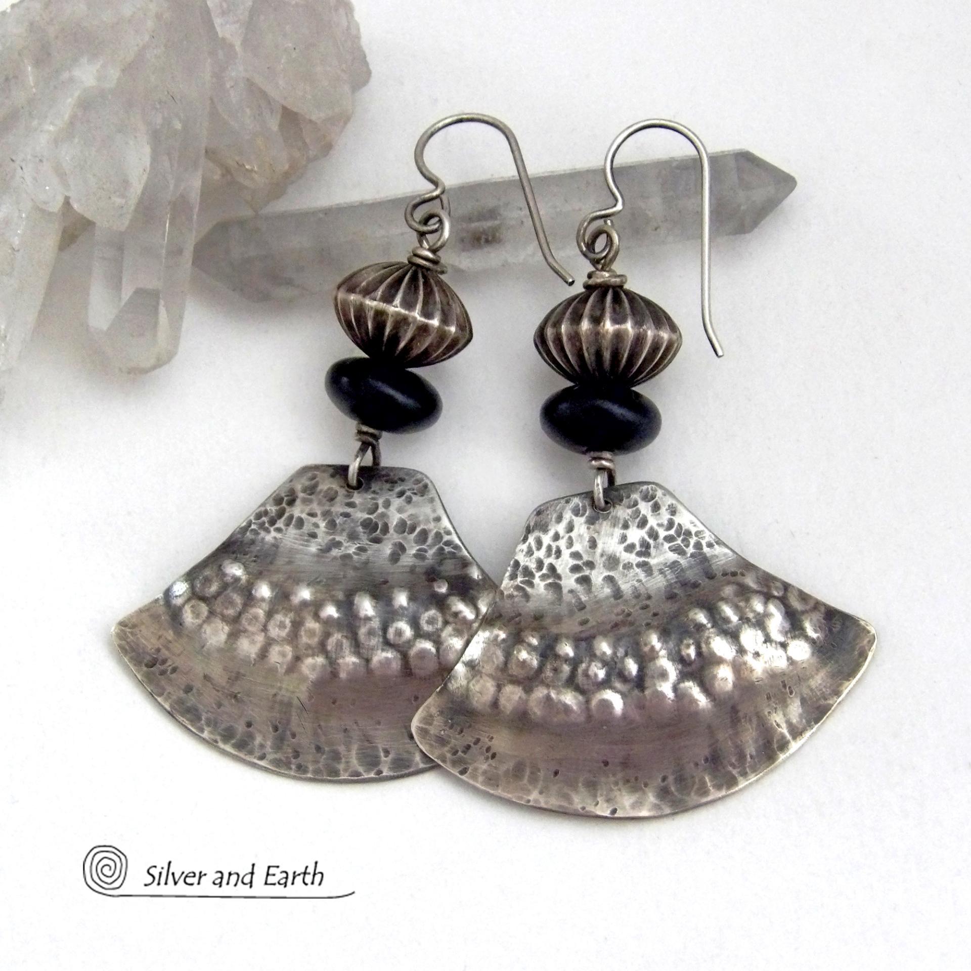 These handcrafted sterling silver earrings have a modern southwestern flair. The sterling shapes have a hammered and stamped texture with an oxidized finish. They are accented with Native Navajo pearl style oxidized sterling silver beads with a rich, corrugated texture and matte black glass beads. Unique and striking, they'll make a bold statement. Handmade in the USA by Silver and Earth Jewelry.