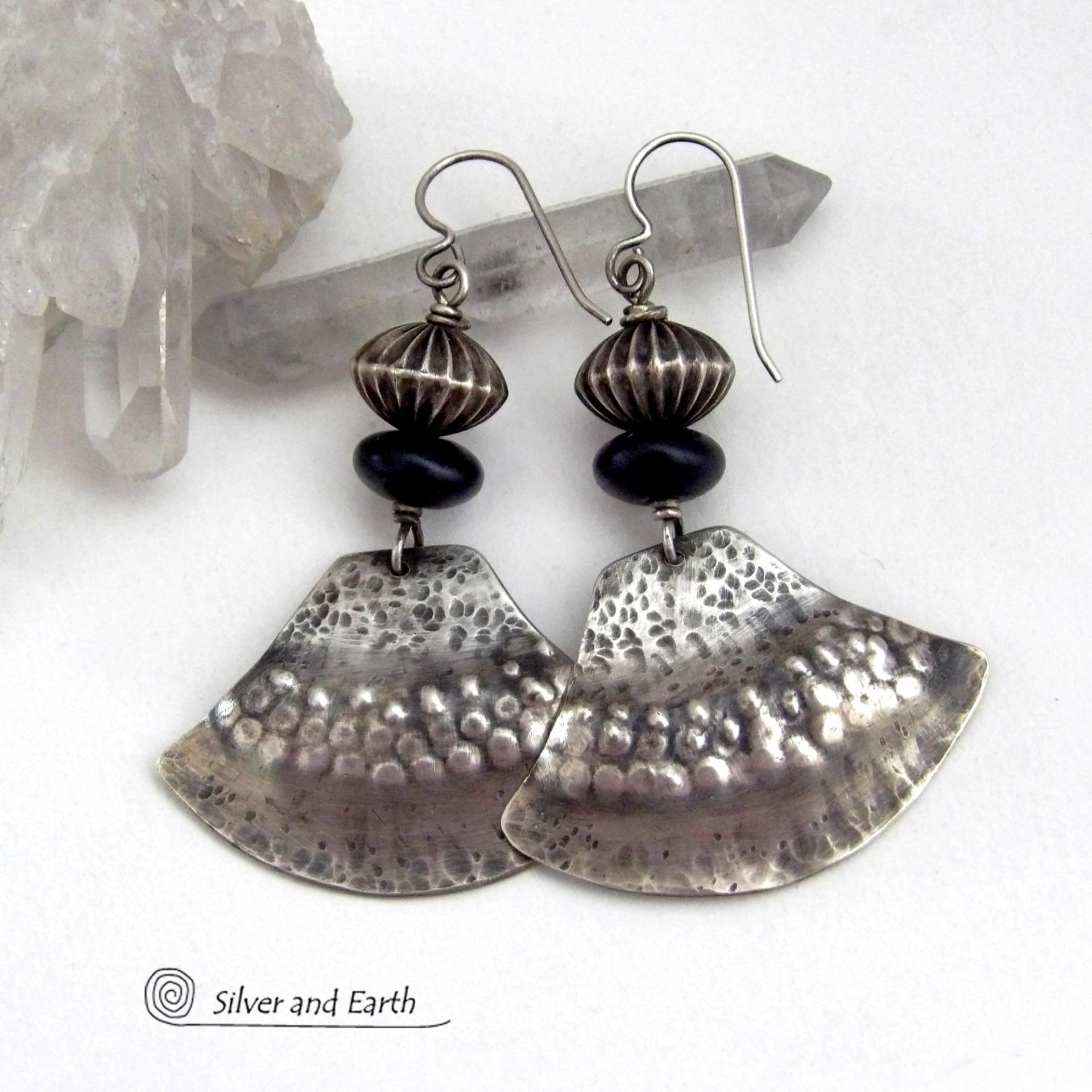 These handcrafted sterling silver earrings have a modern southwestern flair. The sterling shapes have a hammered and stamped texture with an oxidized finish. They are accented with Native Navajo pearl style oxidized sterling silver beads with a rich, corrugated texture and matte black glass beads. Unique and striking, they'll make a bold statement. Handmade in the USA by Silver and Earth Jewelry.