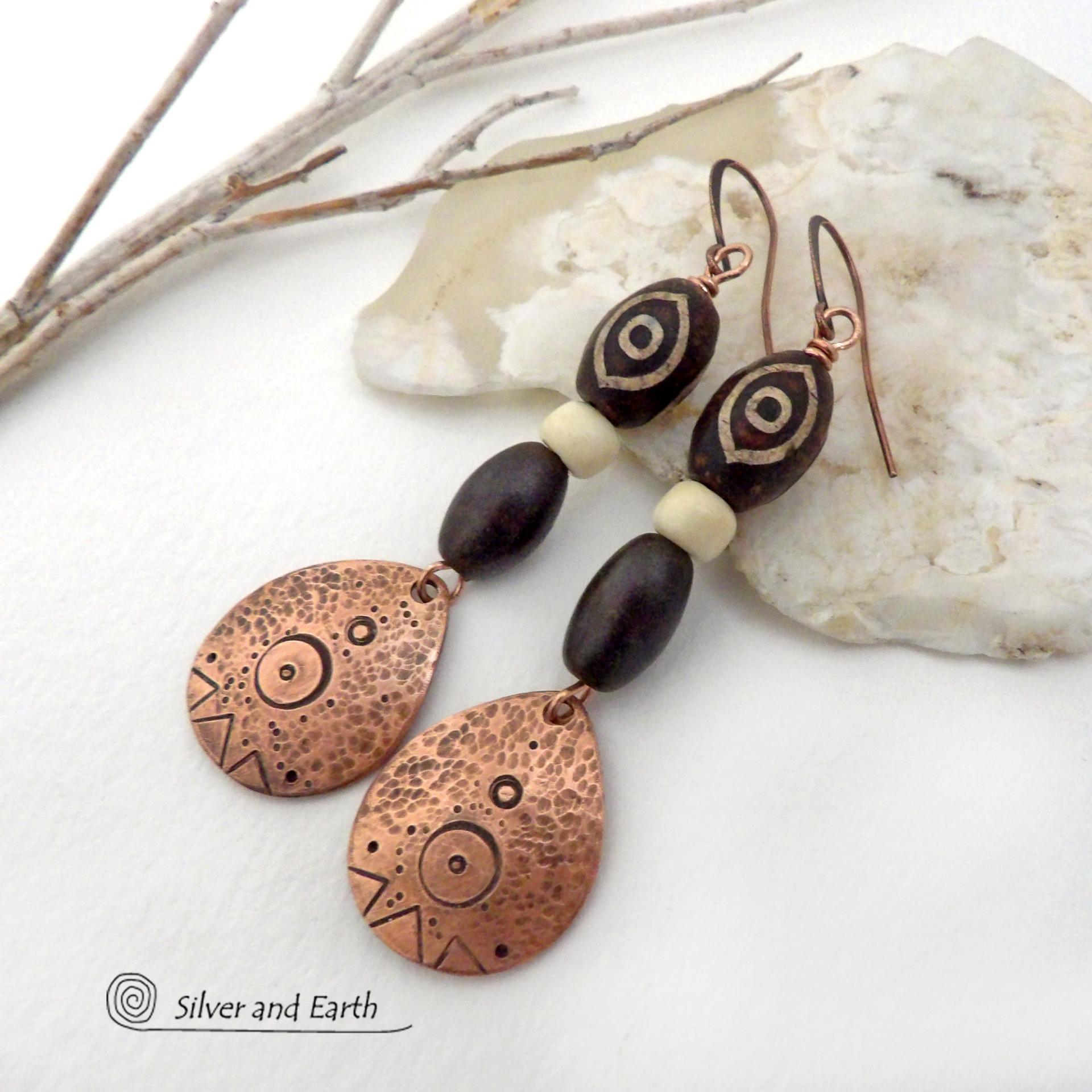 These handcrafted earrings feature copper teardrop shaped dangles with a hand stamped and hammered texture accented with Tibetan brown etched agate stones, African glass and brown wood beads. Bold and unique, they have an ethnic tribal style with boho chic flair that makes a striking statement. Perfect for women that love to wear unique and eye-catching artisan handcrafted jewelry. Handmade in the USA by Silver and Earth Jewelry. Your choice of copper or niobium hypoallergenic ear wires.