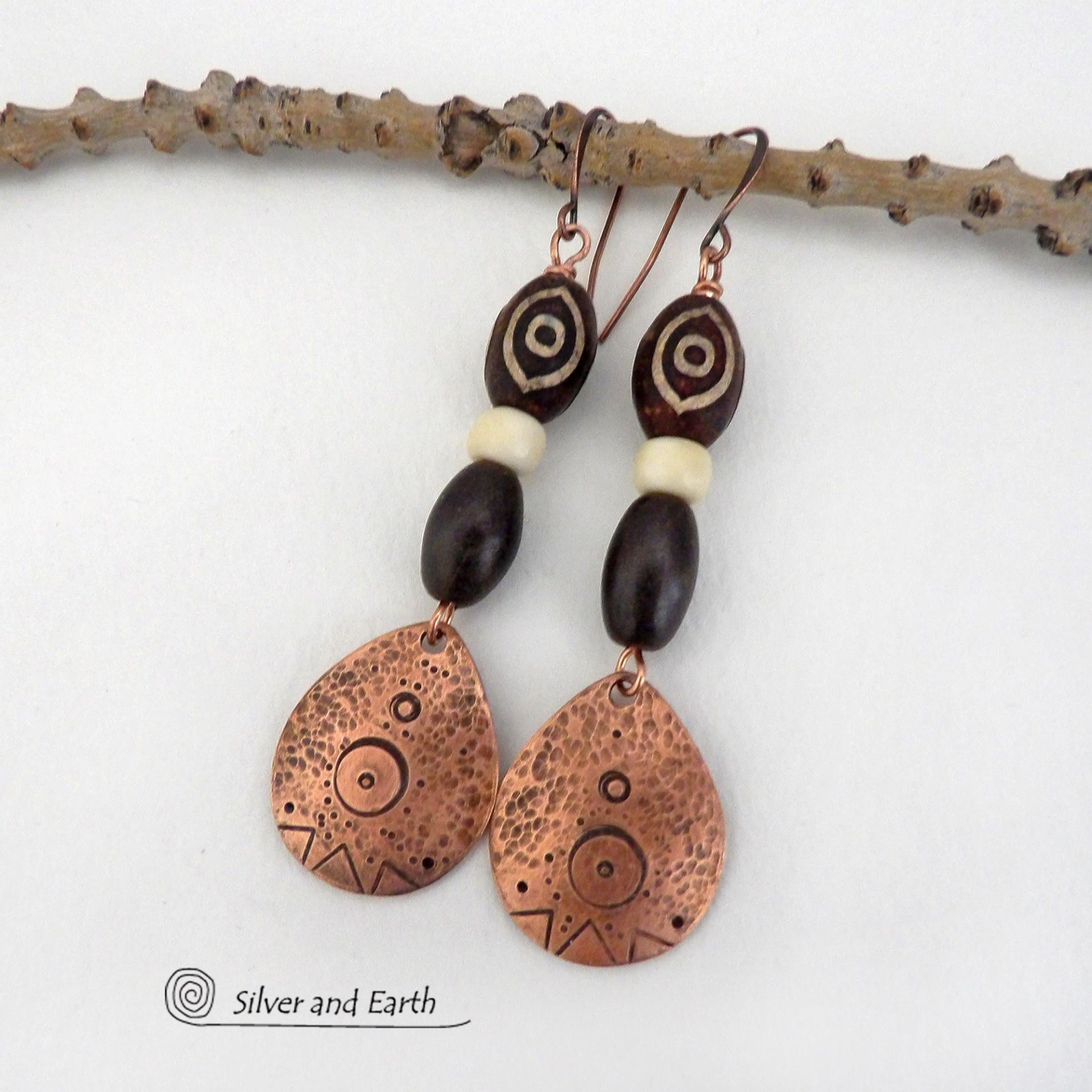 These handcrafted earrings feature copper teardrop shaped dangles with a hand stamped and hammered texture accented with Tibetan brown etched agate stones, African glass and brown wood beads. Bold and unique, they have an ethnic tribal style with boho chic flair that makes a striking statement. Perfect for women that love to wear unique and eye-catching artisan handcrafted jewelry. Handmade in the USA by Silver and Earth Jewelry. Your choice of copper or niobium hypoallergenic ear wires.