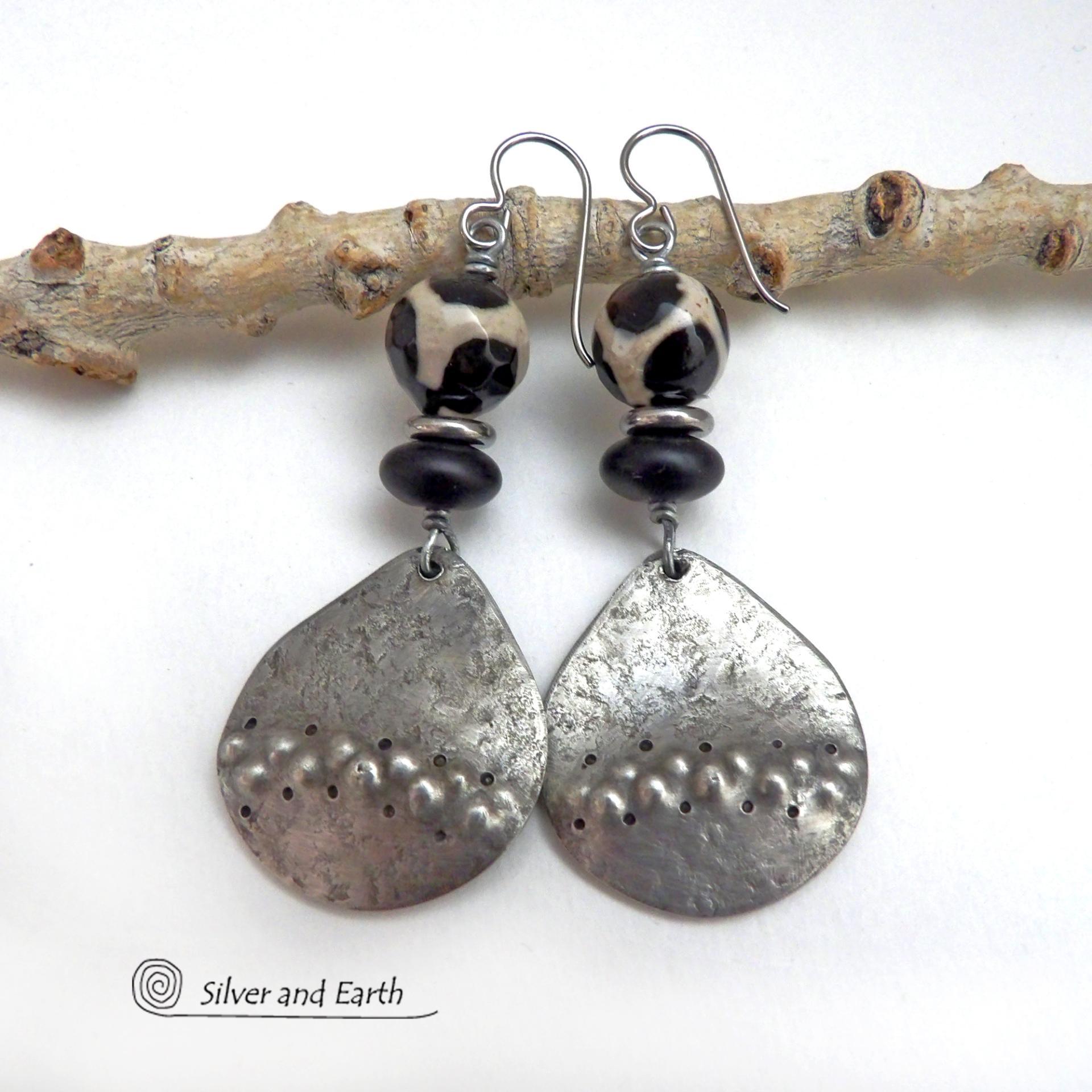 These handcrafted silver pewter earrings have a rustic, hammered texture and are accented with black and off-white Tibetan agate faceted gemstones, black glass and stainless steel beads. Bold and striking, they'll make a unique ethnic tribal statement. Perfect for women that love to wear unique, eye-catching jewelry. Handmade in the USA by Silver and Earth Jewelry.  MEASUREMENTS: Total length of approximately 2-1/2" from top of silver niobium (hypoallergenic) ear wires and 1” at widest point.